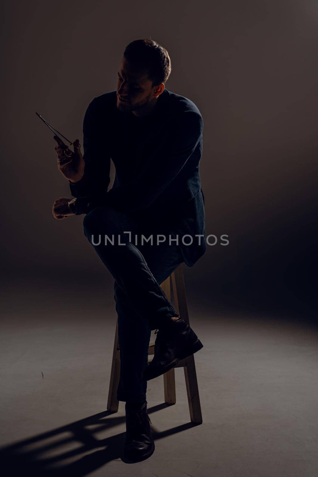 Doctor with surgical equipment needle and scissors. Handsome man weared casual business suit. Portrait of surgeon in studio