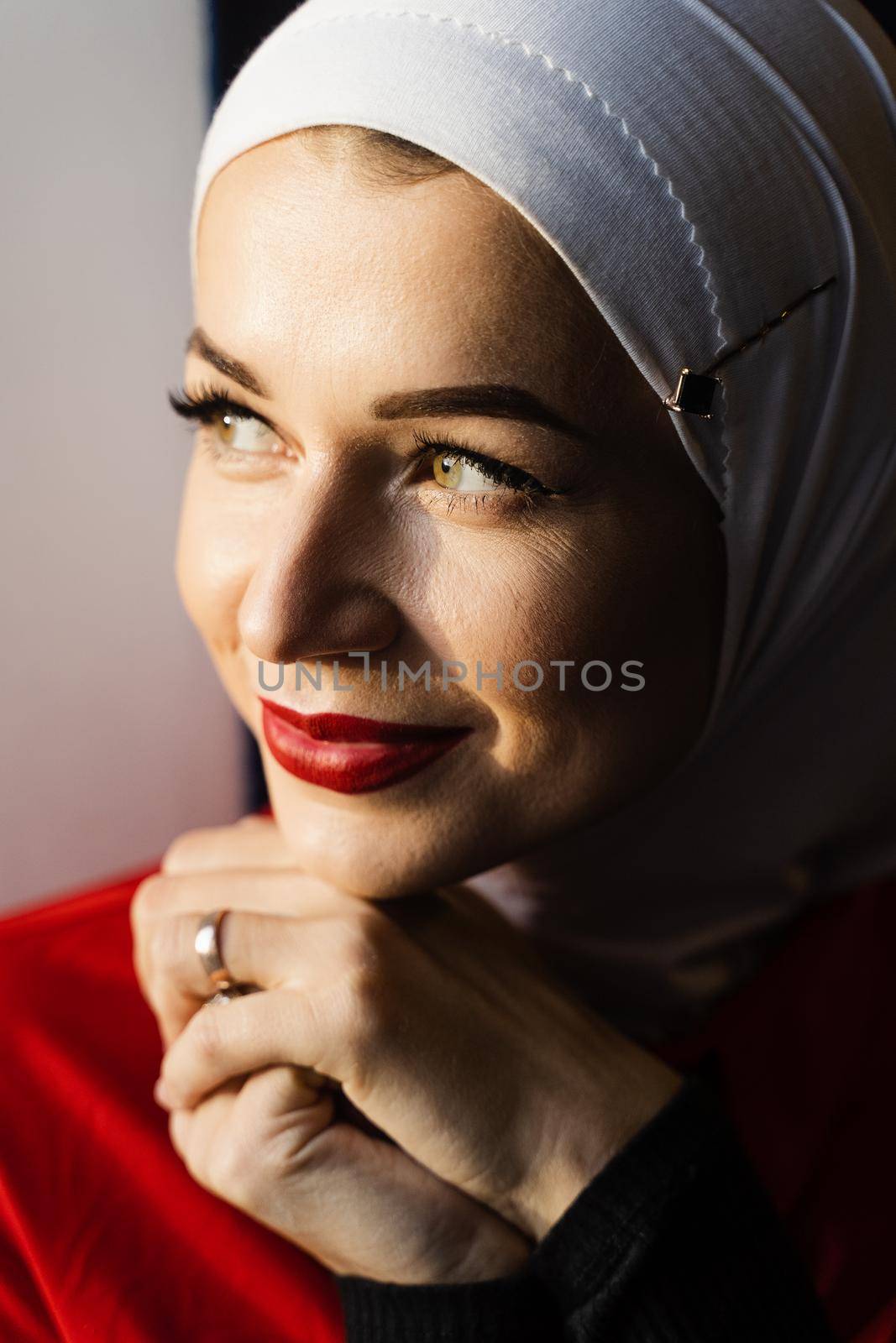 Muslim girl is praying at home. Close-up portrait of muslim model weared in traditional islamic scarf. Islam religion