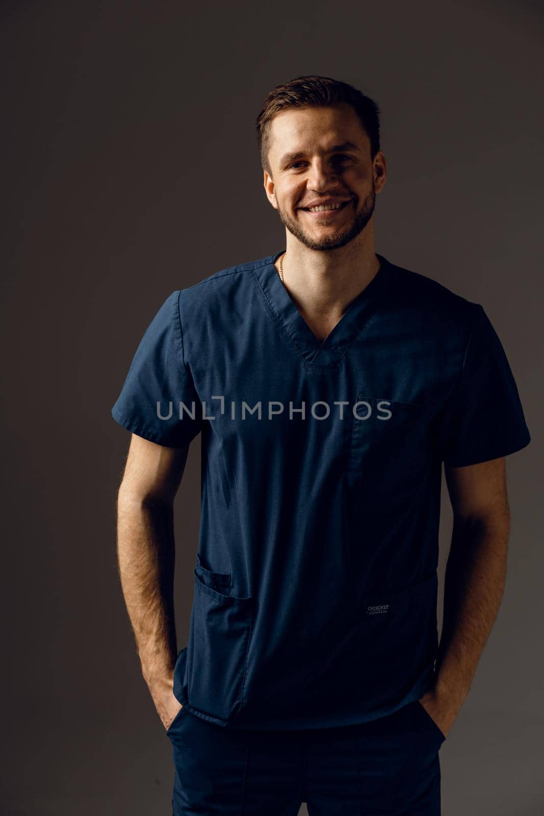 Surgeon weared in medical robe on dark background. Handsome doctor posing in studio