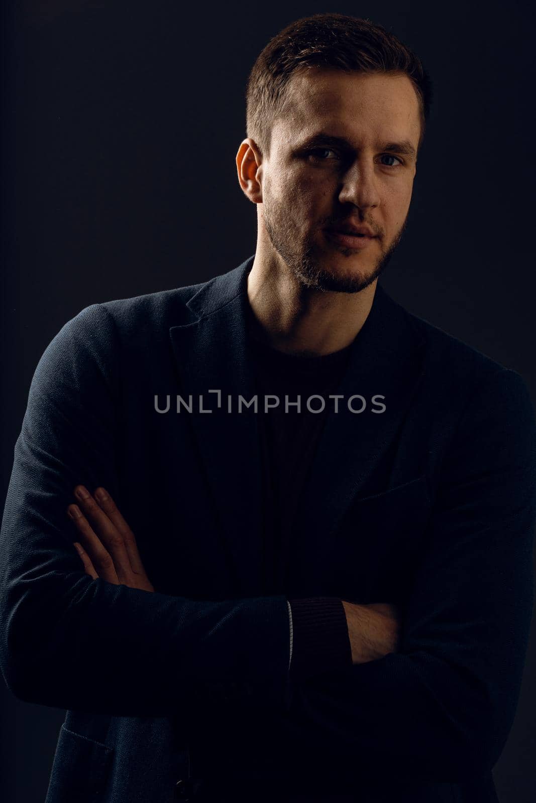 Confident professional fashion male posing in studio. Business man portrait on dark background. Handsome young man weared suit.