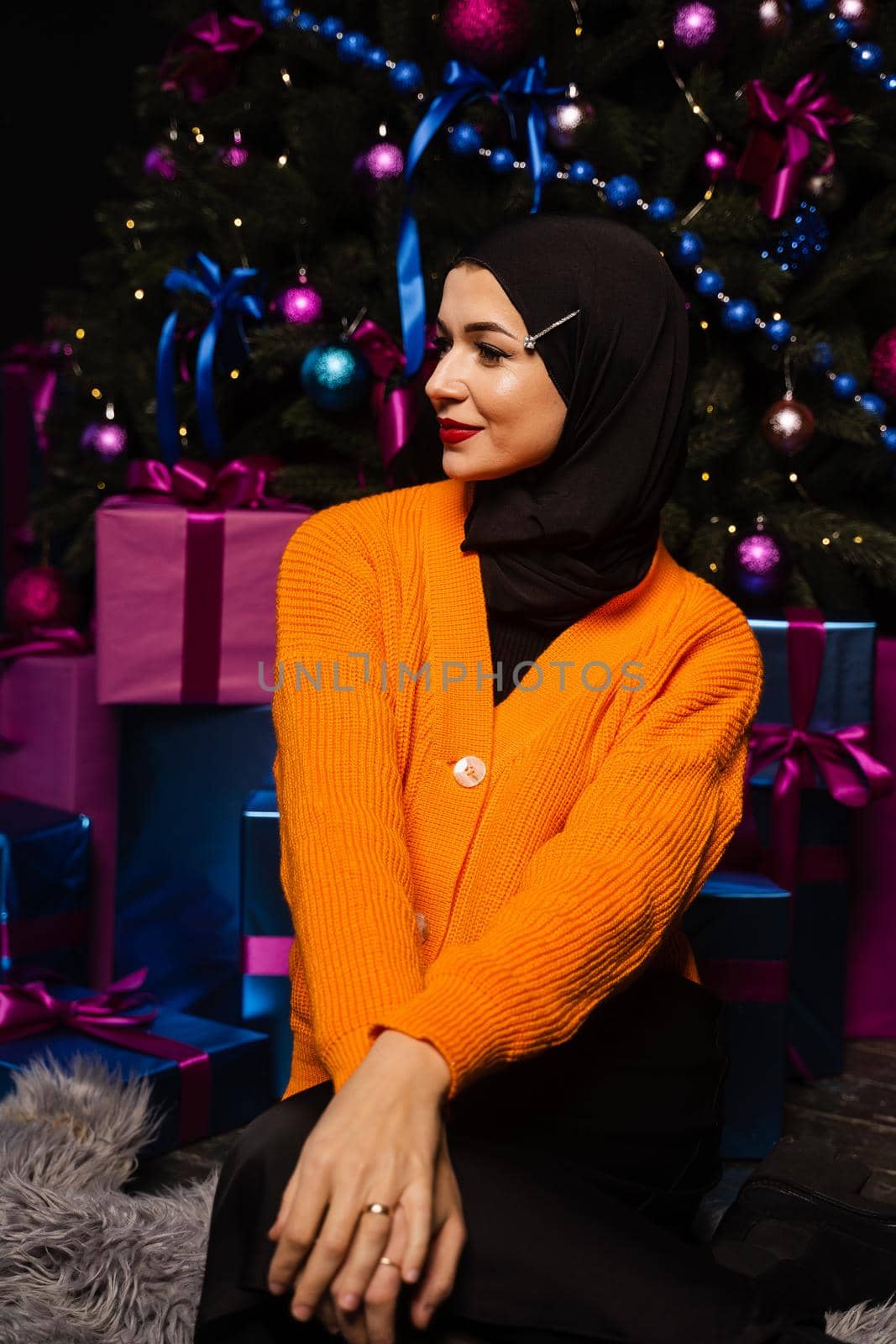 Muslim girl in black hijab is dreaming about gift at new year holiday. Christmas celebration of islamic religion people. by Rabizo