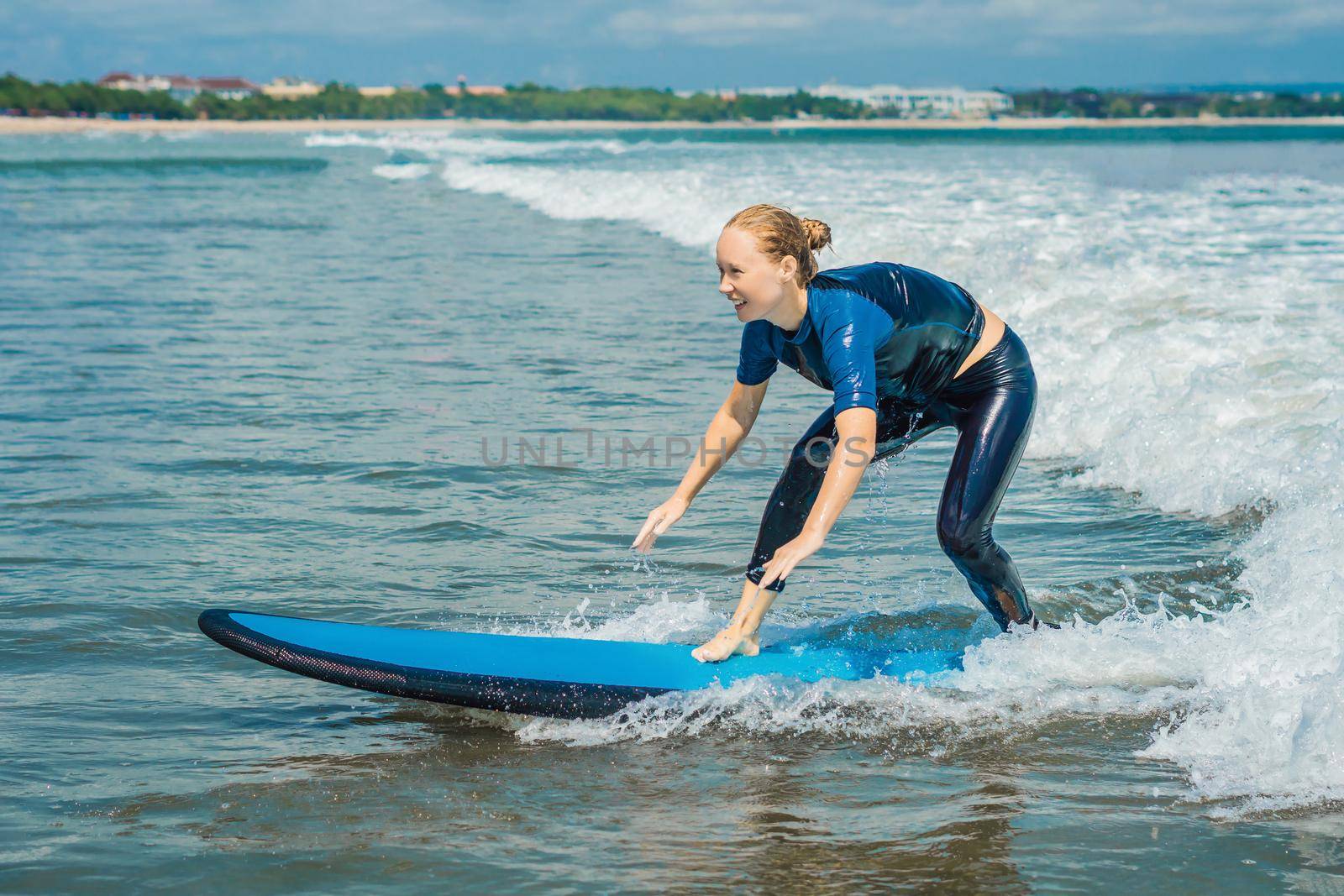 Joyful young woman beginner surfer with blue surf has fun on small sea waves. Active family lifestyle, people outdoor water sport lesson and swimming activity on surf camp summer vacation.