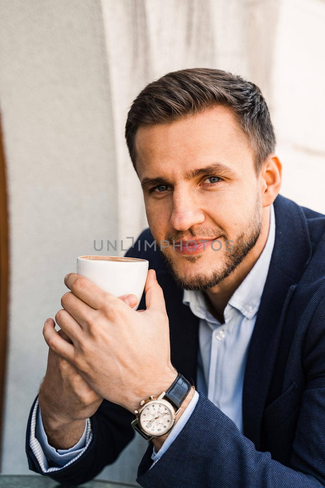 Man like coffee. Handsome man with cup of coffee in cafe. Morning lifestyle of male. Man is sitting on the summer terrace in cafe, drinking coffee and smiling