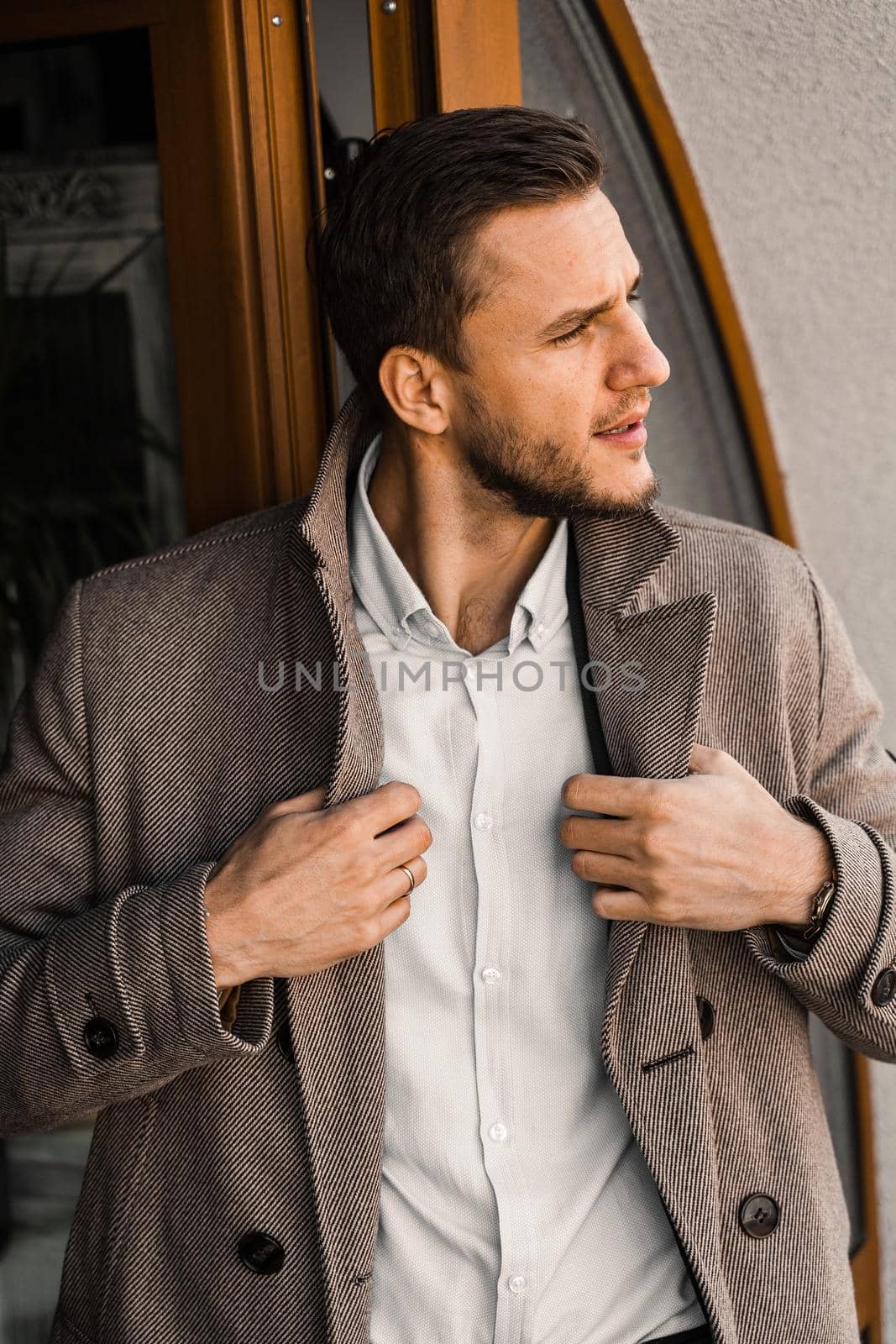 Handsome bearded business man in coat posing outside. Male lifestyle