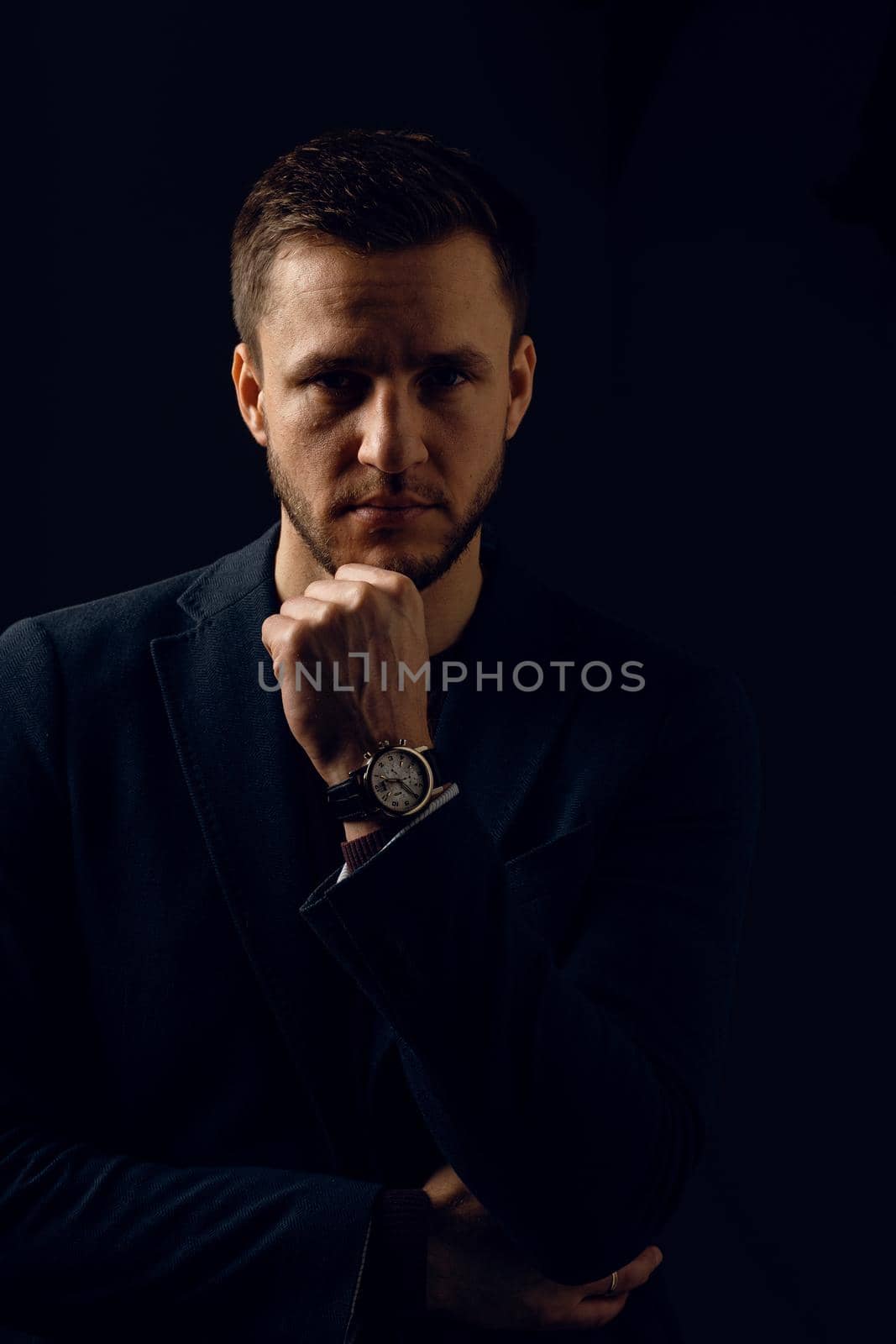 Confident professional fashion male posing in studio. Business man portrait on dark background. Handsome young man weared suit.