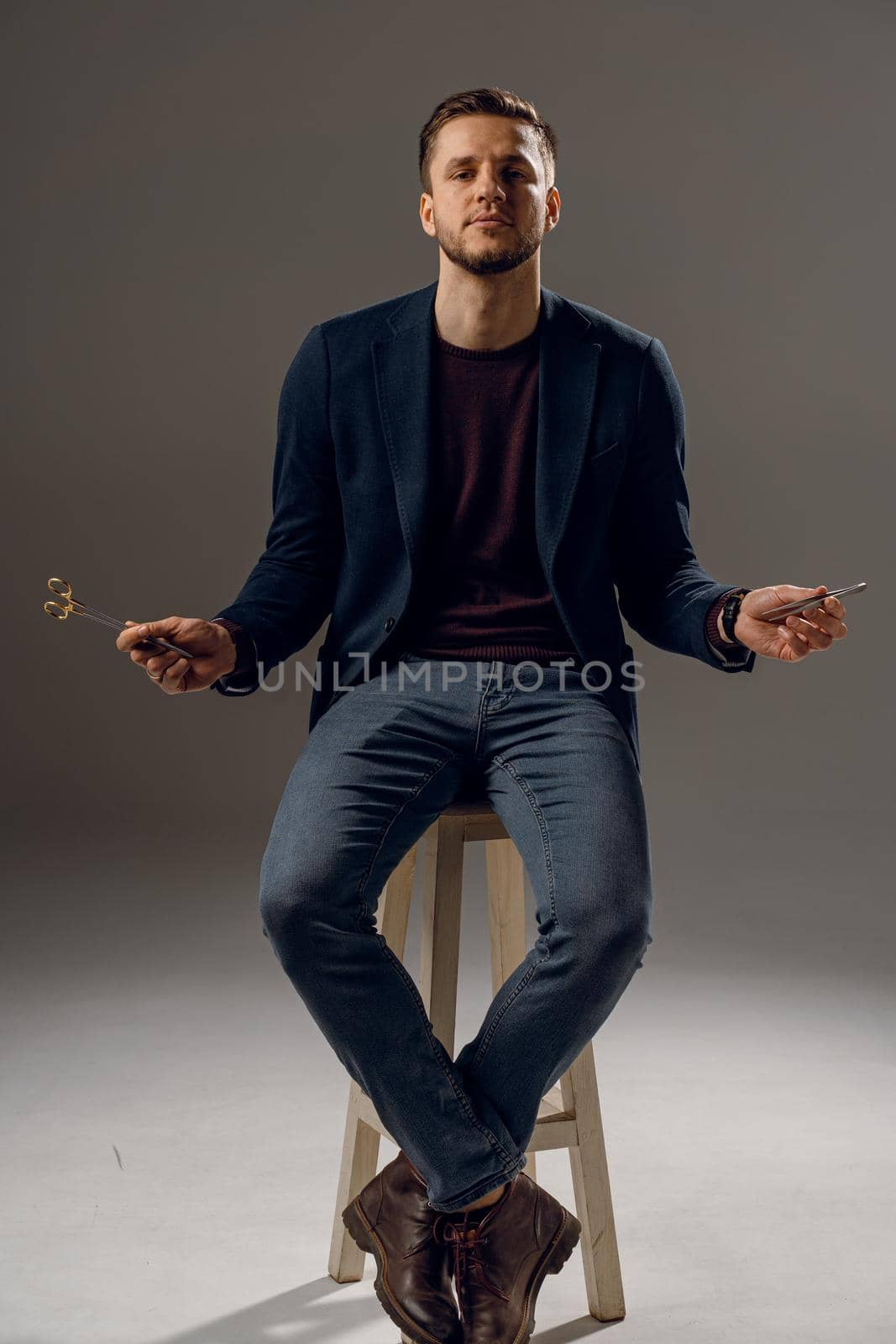 Handsome surgeon with needle holder and surgical knife weared casual suit in studio. Confident business man on dark background