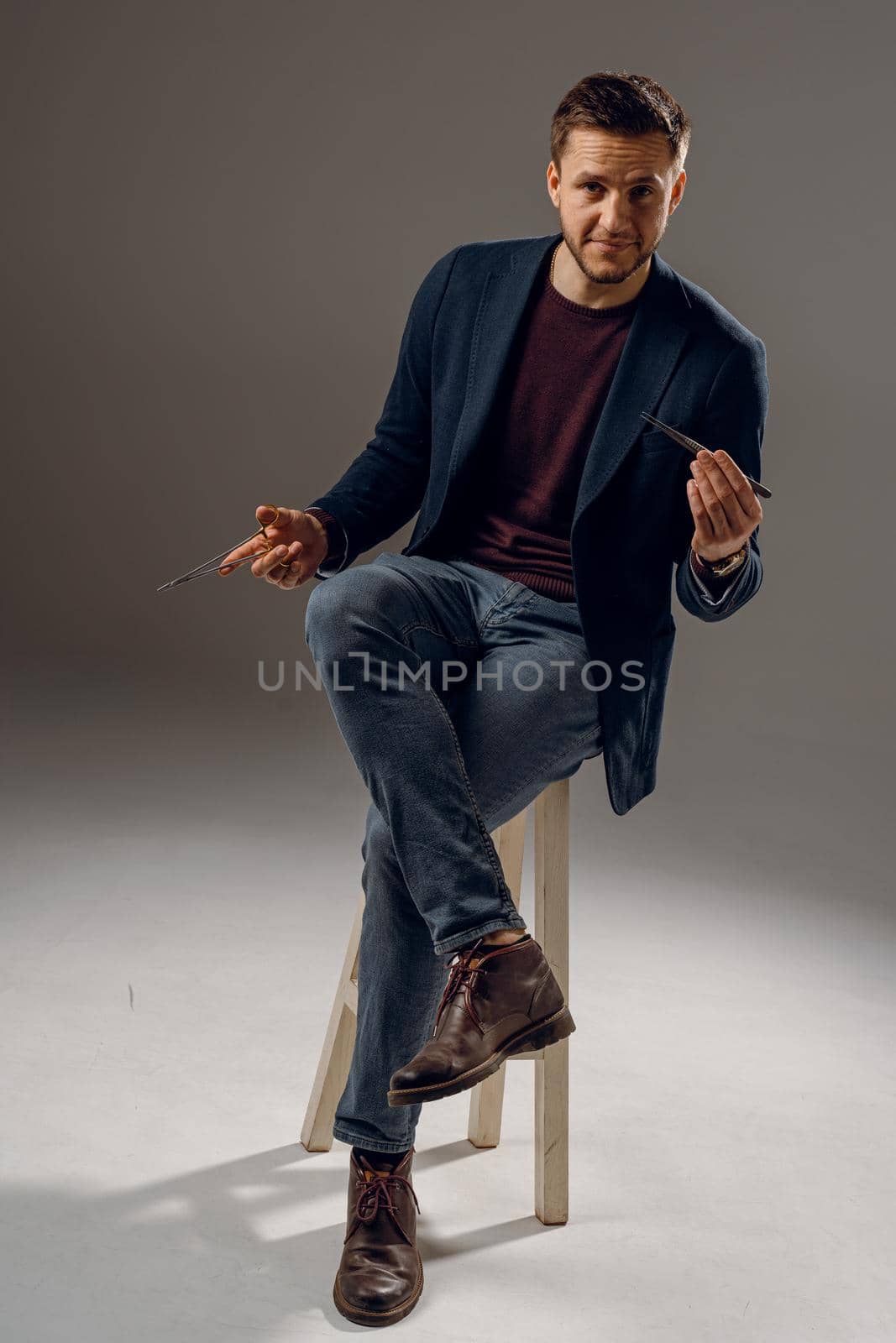 Handsome surgeon with needle holder and surgical knife weared casual suit in studio. Confident business man on dark background