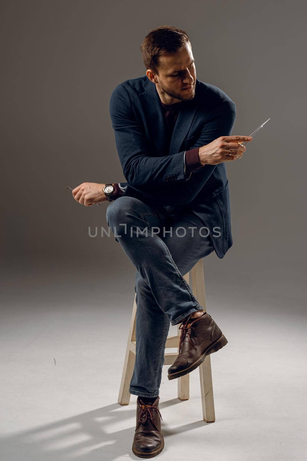 Doctor with surgical equipment needle and scissors. Handsome man weared casual business suit. Portrait of surgeon in studio