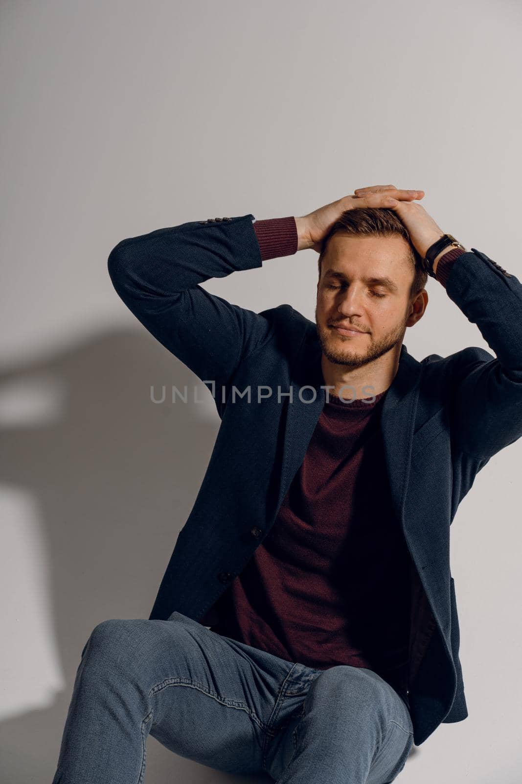 Handsome man smiling and posing in studio on white background. Confident male touches his hair. Feeling freedom, by Rabizo