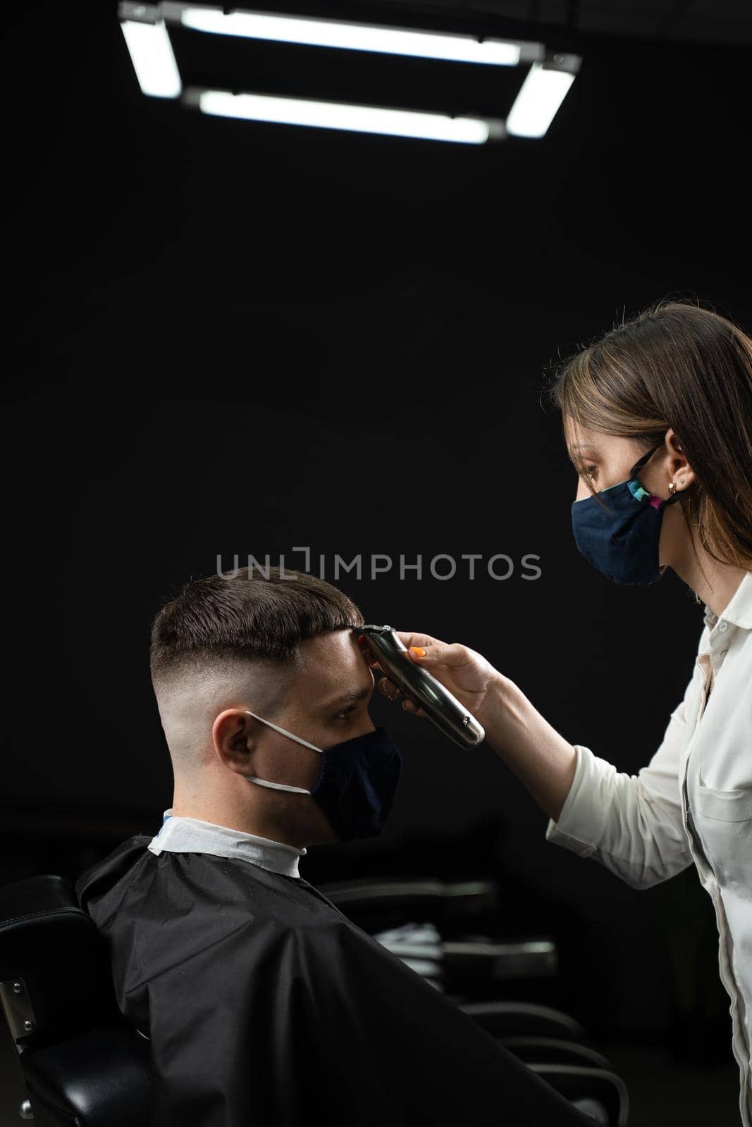 Barbershop customer in medical mask for protection against coronavirus covid-19. Making hairstyle for handsome man. by Rabizo