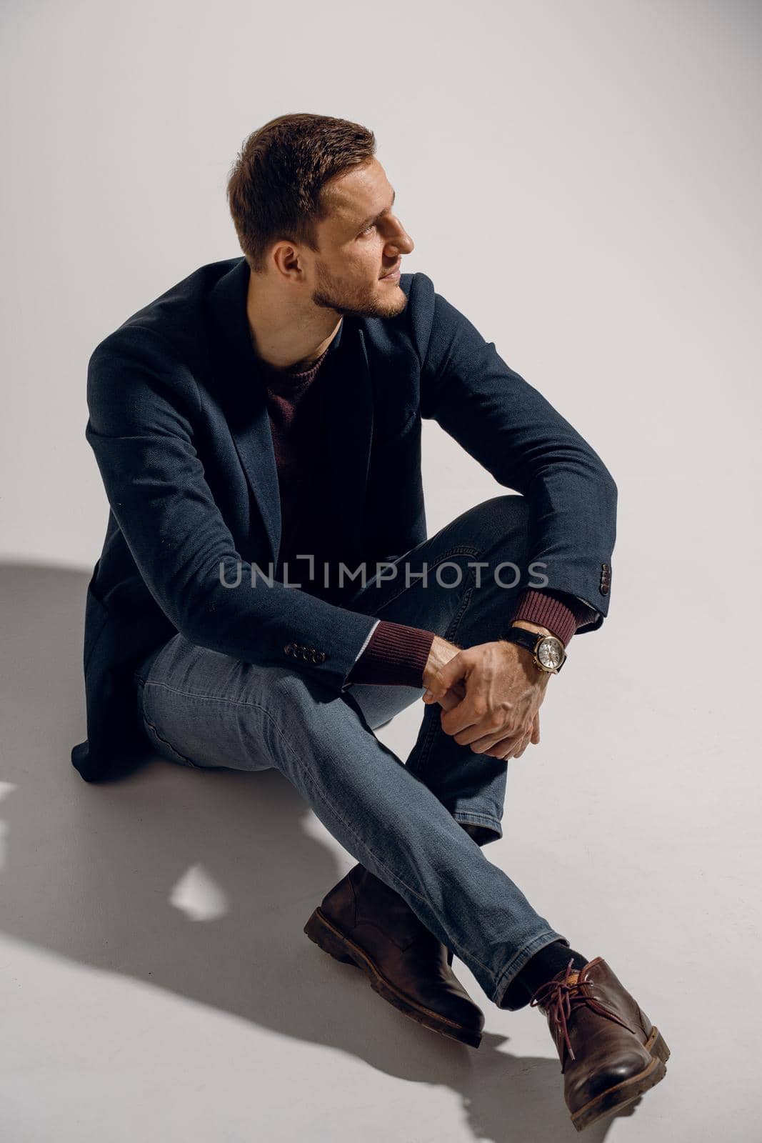 Fashion business man model posing in the studio. Confident male weared casual suit by Rabizo