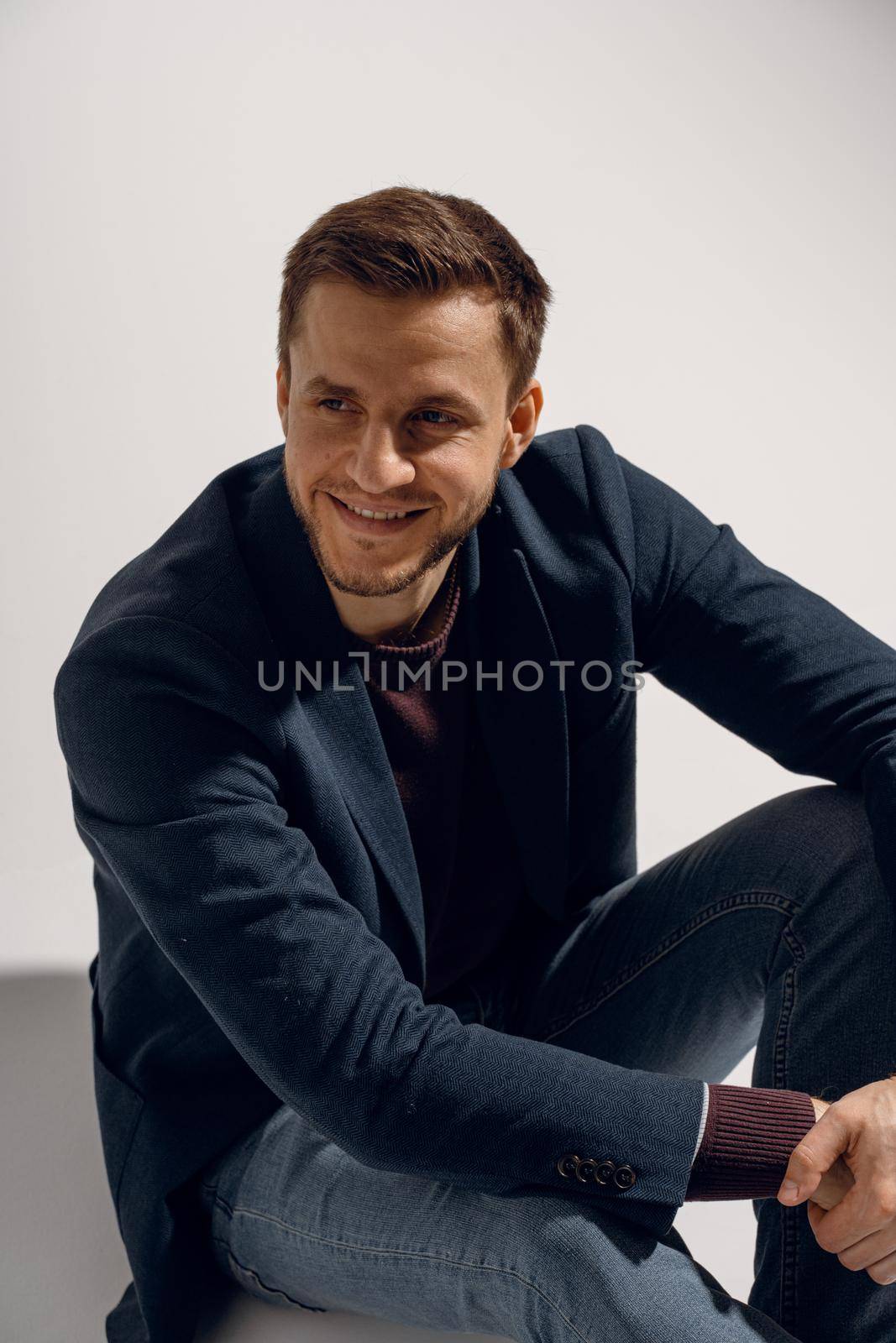 Handsome man smiling and posing in studio on white background. Confident male touches his hair. Feeling freedom, by Rabizo