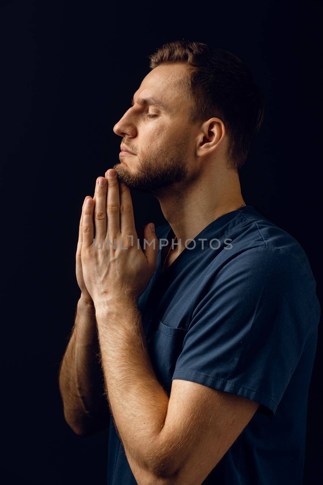 Man cover his face with his hands and thinks about life. Handsome man pray and believe in God. Orthodox Christian faith by Rabizo