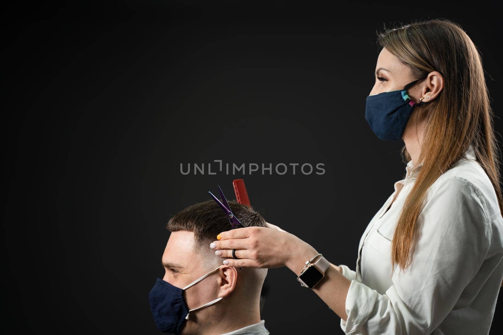 Barbershop service at coronavirus covid-19 period. Woman barber making hair for handsome man. Using mask. by Rabizo