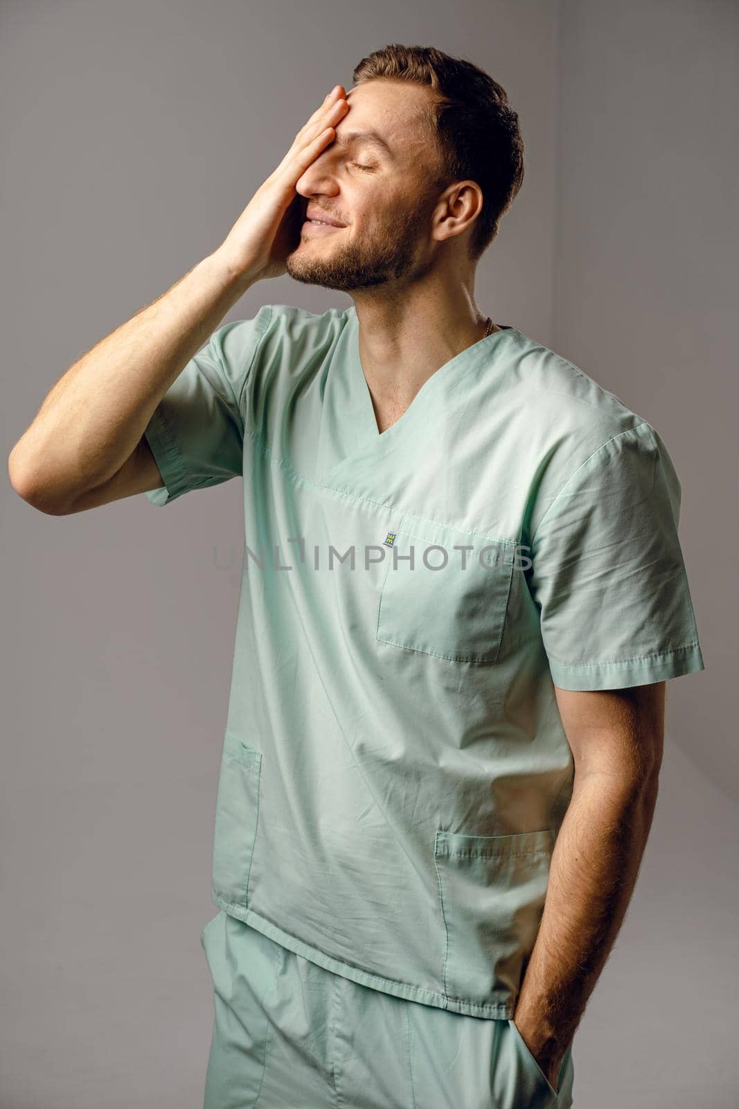 Surgeon weared in medical robe smile and posing on white background. Handsome happy doctor posing in studio