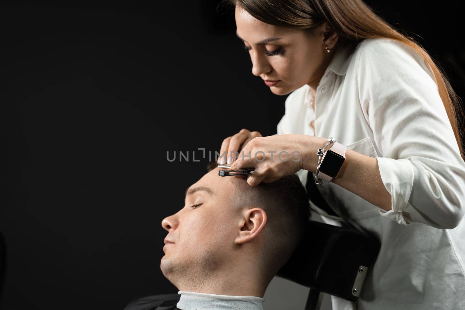 Straight razor cut man hair in barbershop. Attractive woman barber making hairstyle for handsome man. by Rabizo