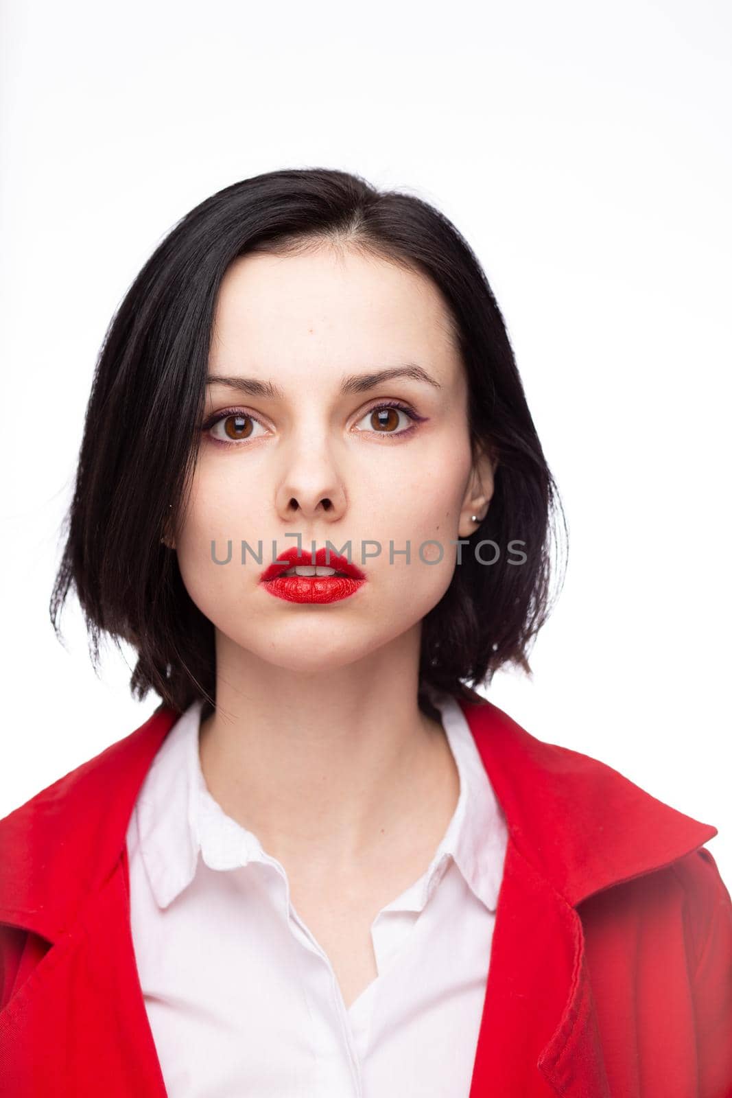 brunette woman with red lipstick on her lips in a red jacket and white shirt, white background. High quality photo