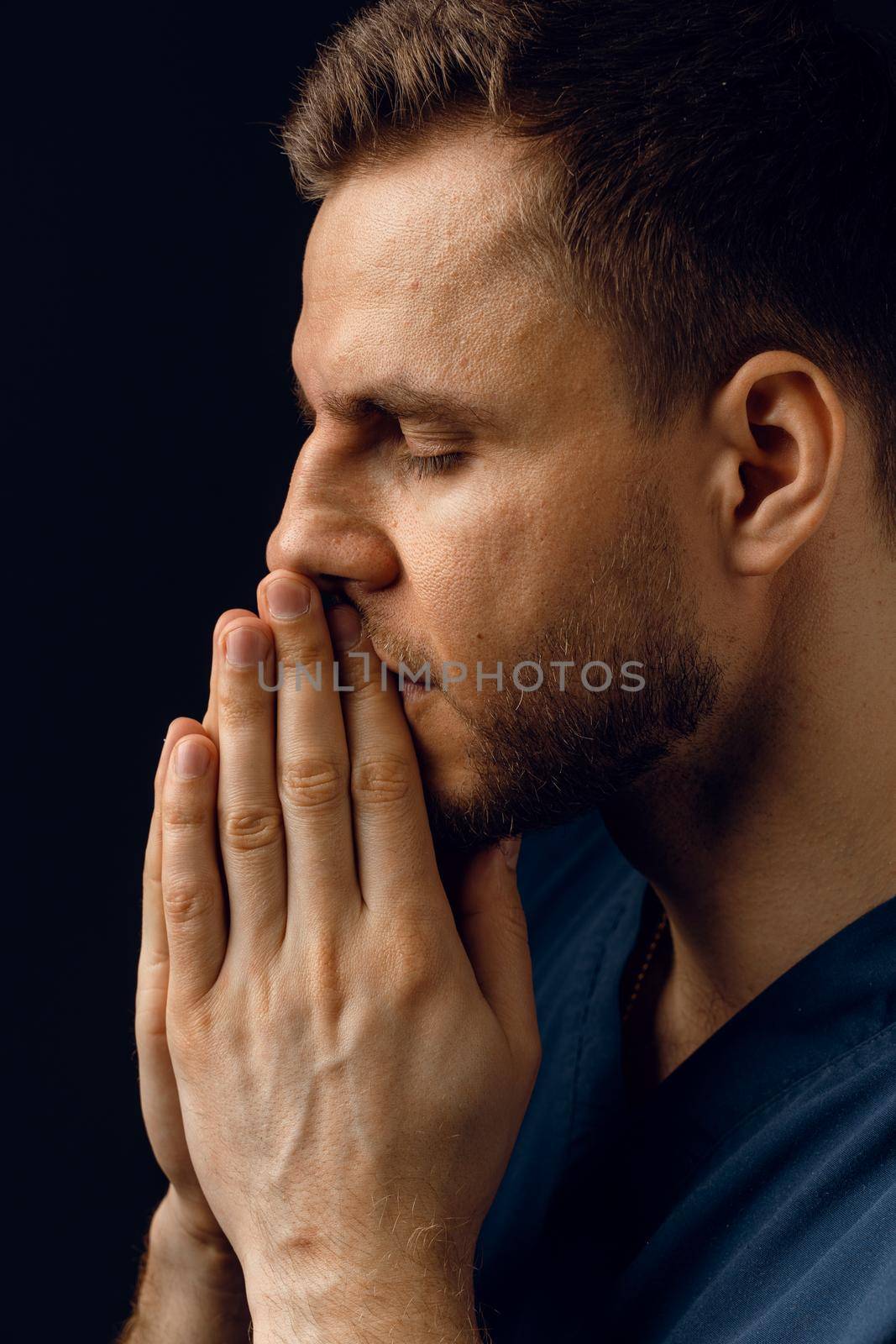 Handsome man pray and believe in God. Orthodox Christian faith. Man cover his face with his hands and thinks about life. by Rabizo