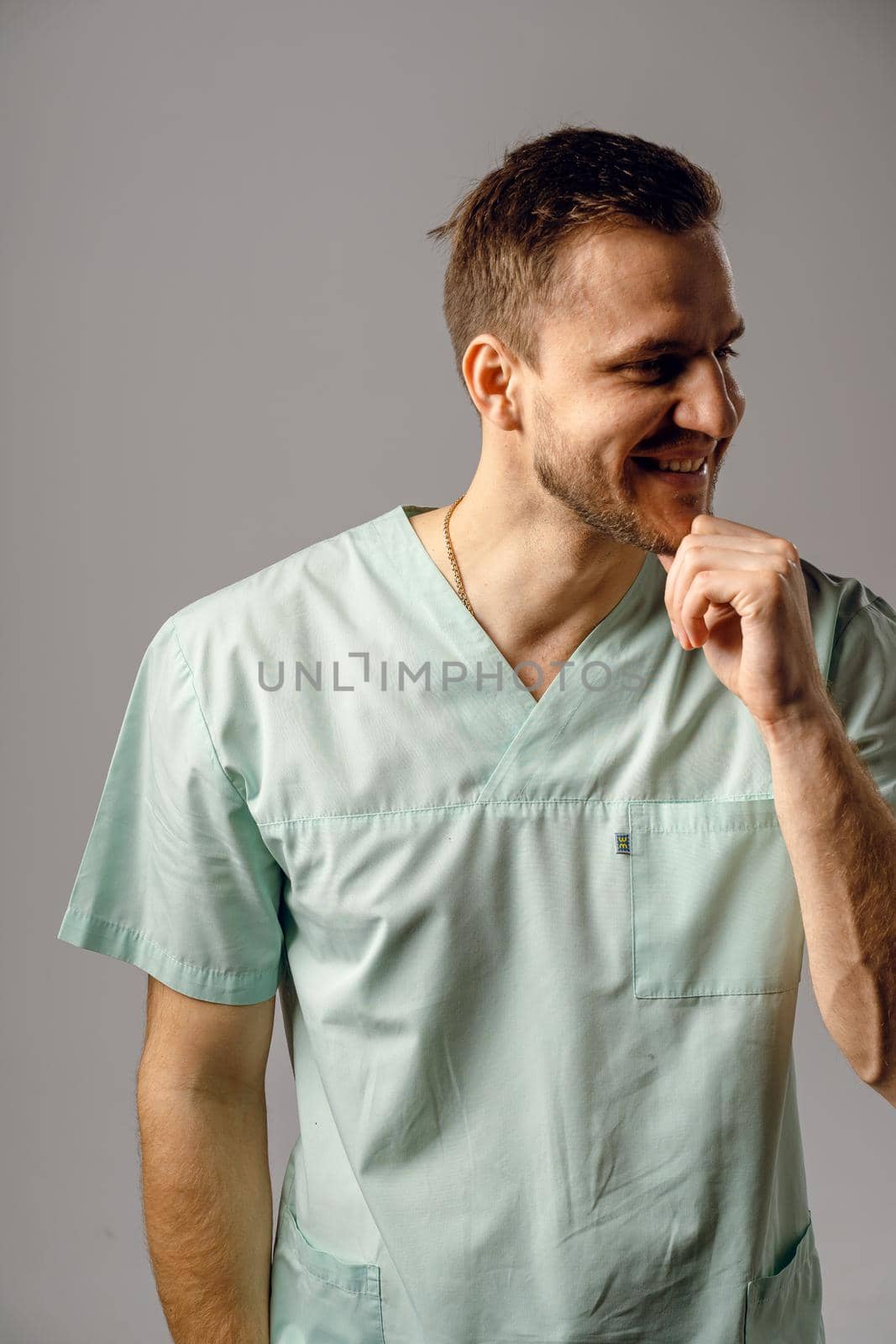 Surgeon weared in medical robe smile and posing on white background. Handsome happy doctor posing in studio