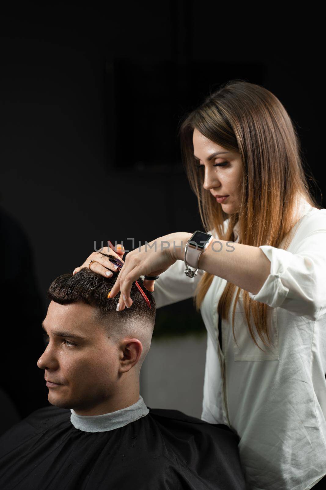 Haircut and styling in barbershop for handsome man. Woman making hairstyle using scissors. by Rabizo