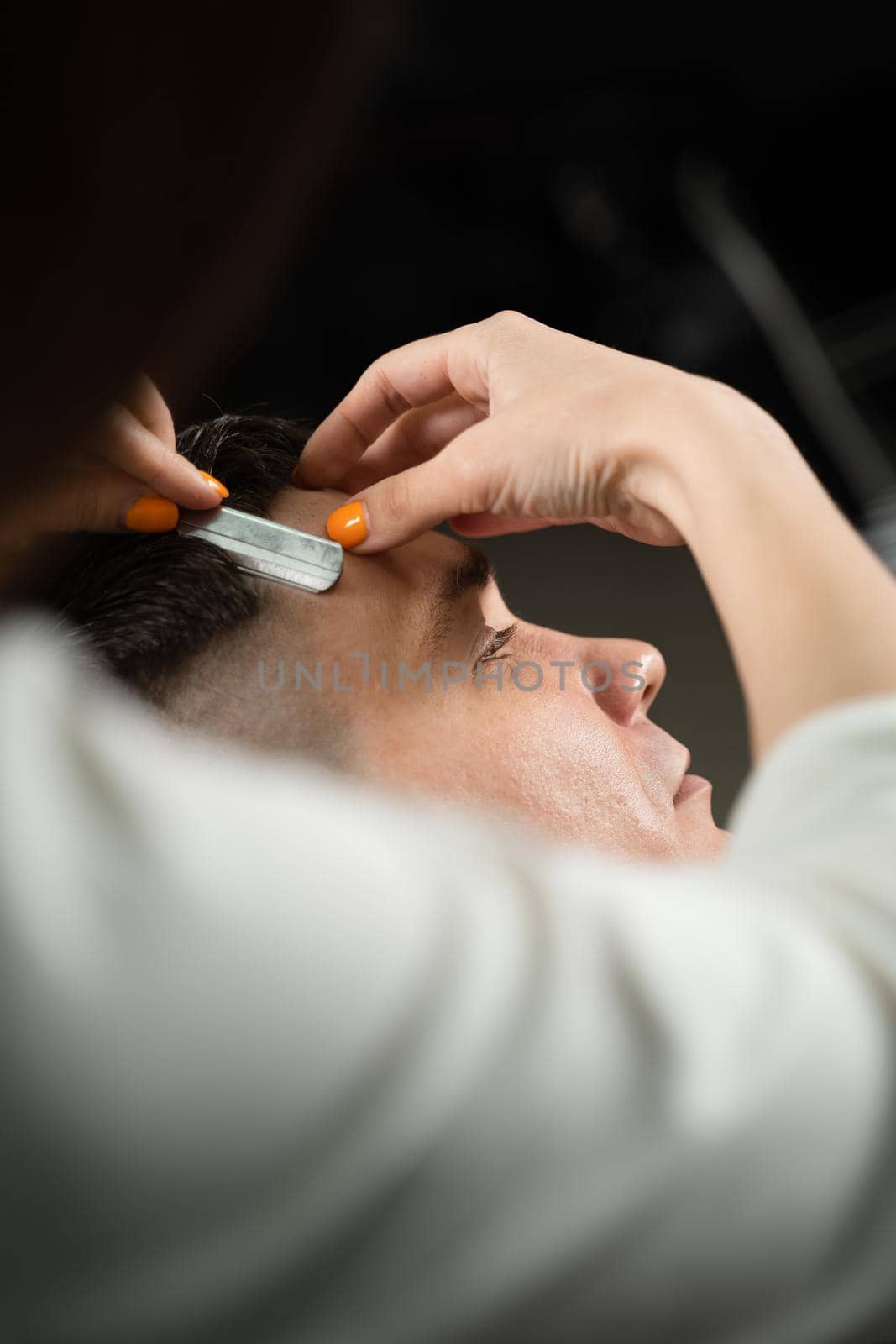 Straight razor cut man hair in barbershop. Attractive woman barber making hairstyle for handsome man. by Rabizo