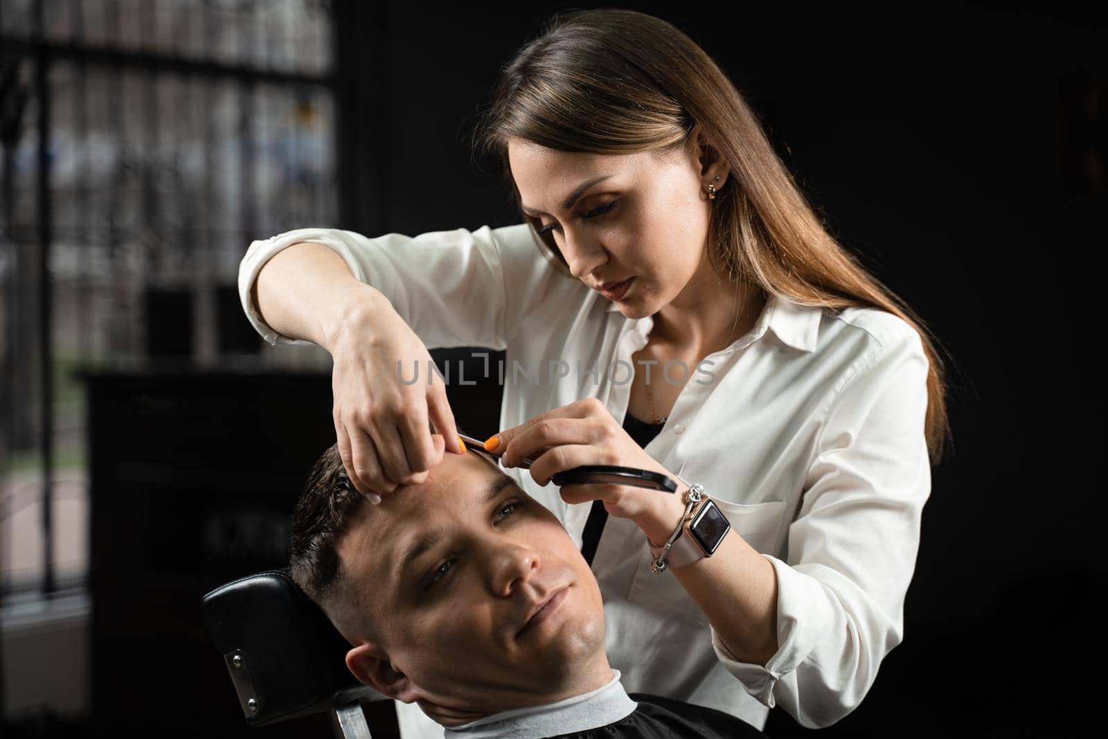 Straight razor cut man hair in barbershop. Attractive woman barber making hairstyle for handsome man. by Rabizo