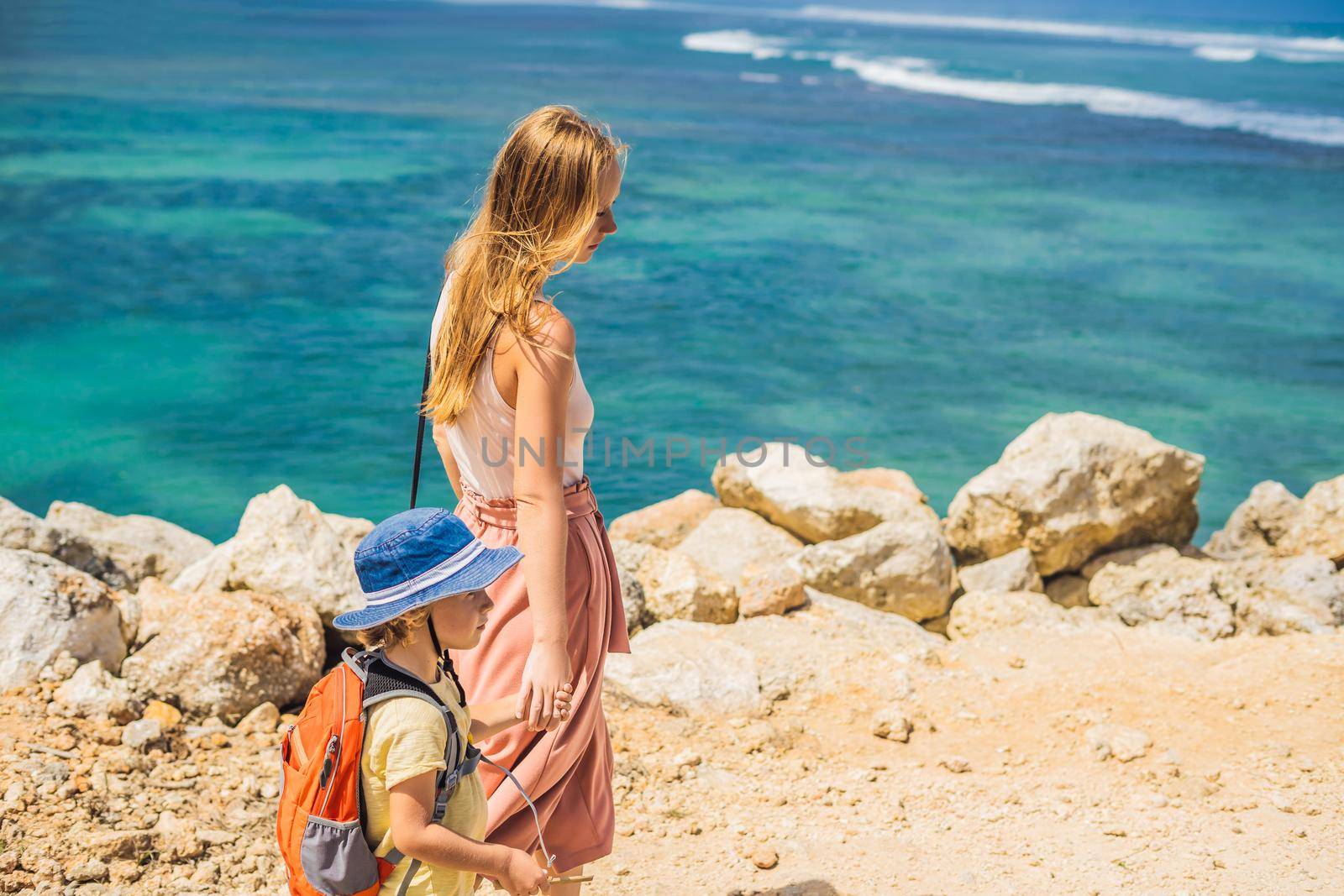 Mom and son travelers on amazing Melasti Beach with turquoise water, Bali Island Indonesia. Traveling with kids concept.