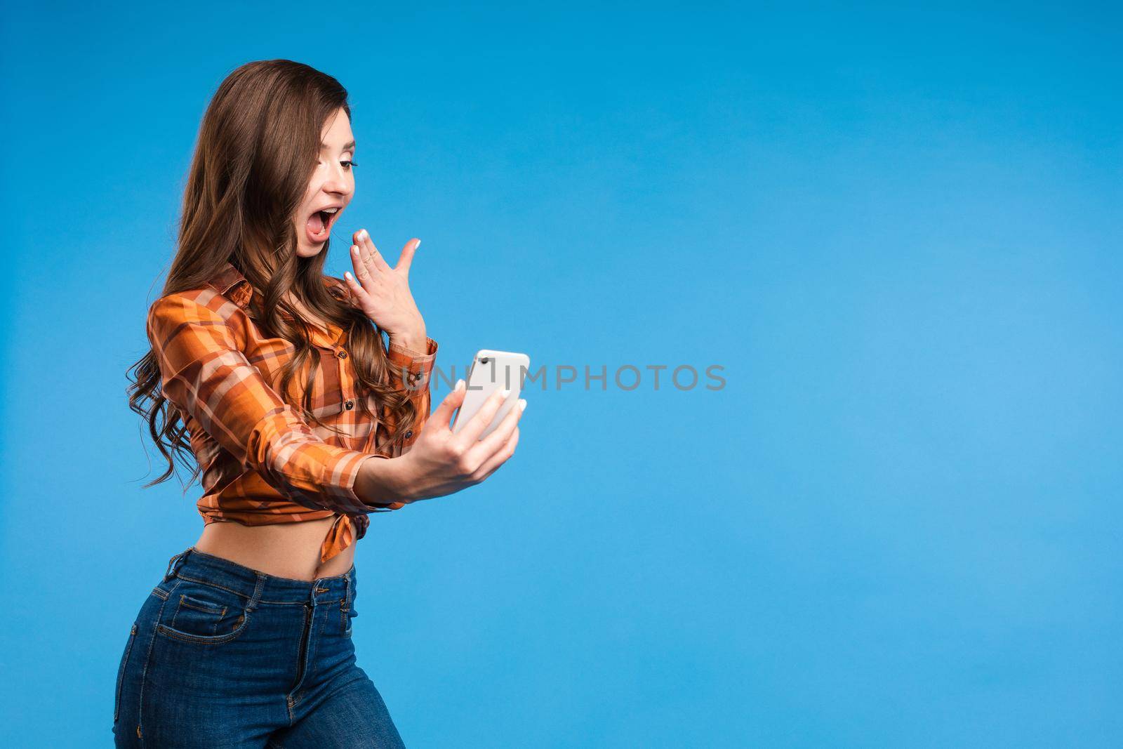 Young alluring girl doing photos She is standing and taking selfie with smartphon by StudioLucky