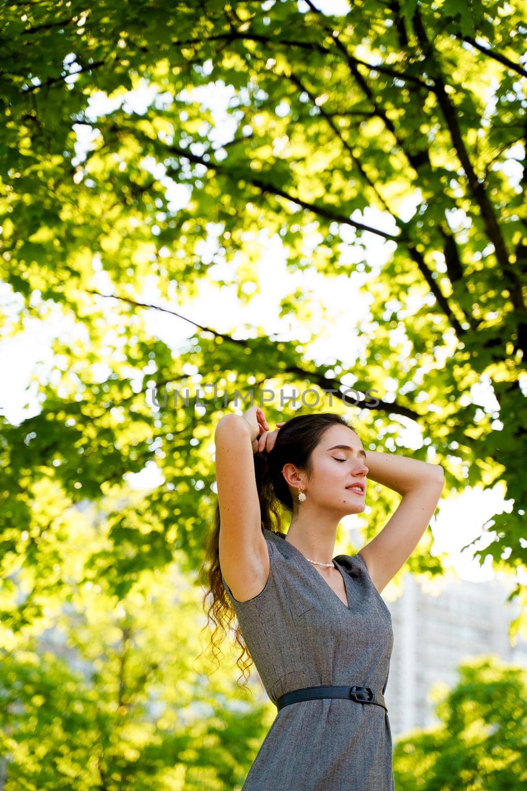 Relaxation and meditation lifestyle of young girl in green park. Vertical photo of beautiful girl who touches and correct her hair by Rabizo