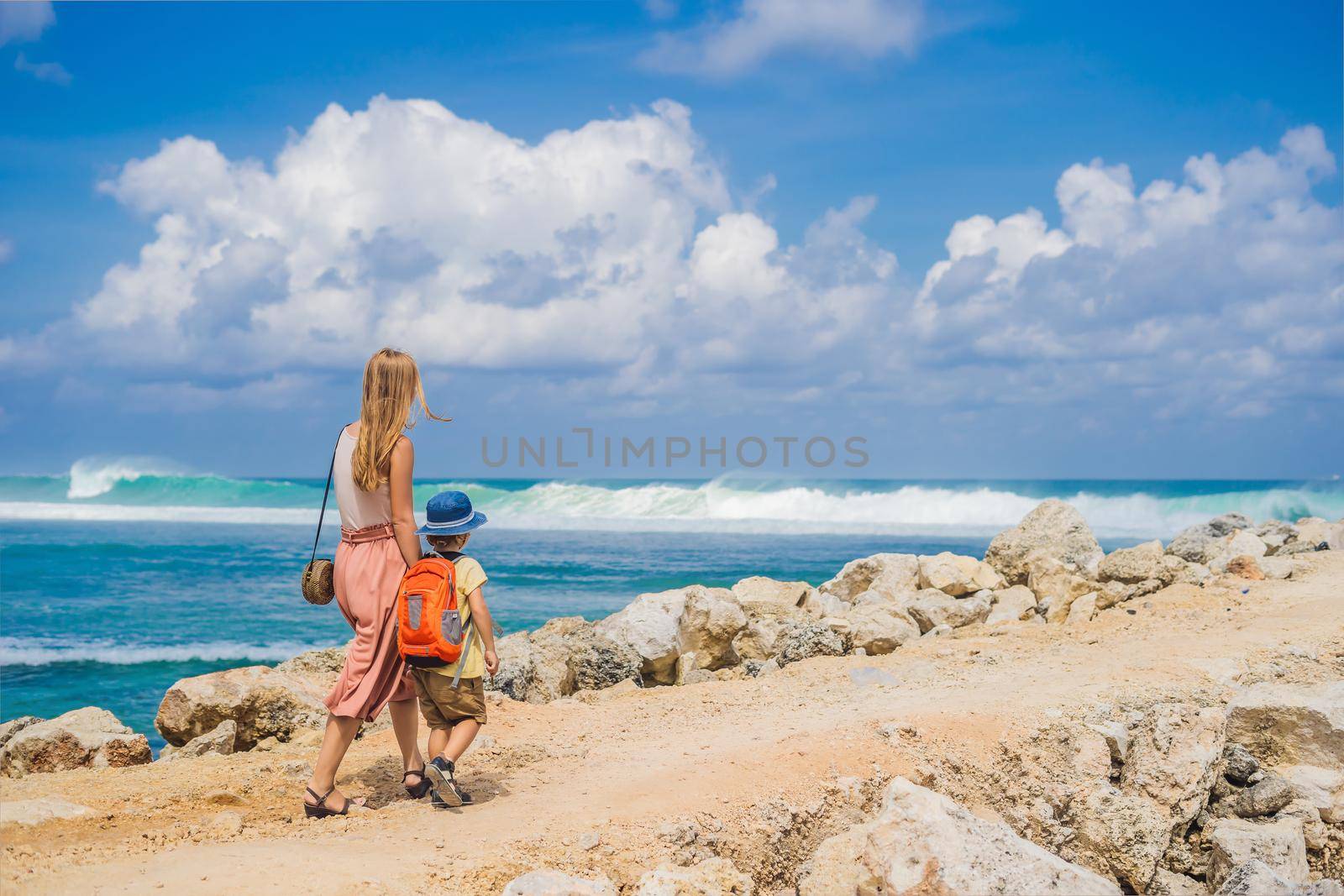 Mom and son travelers on amazing Melasti Beach with turquoise water, Bali Island Indonesia. Traveling with kids concept.