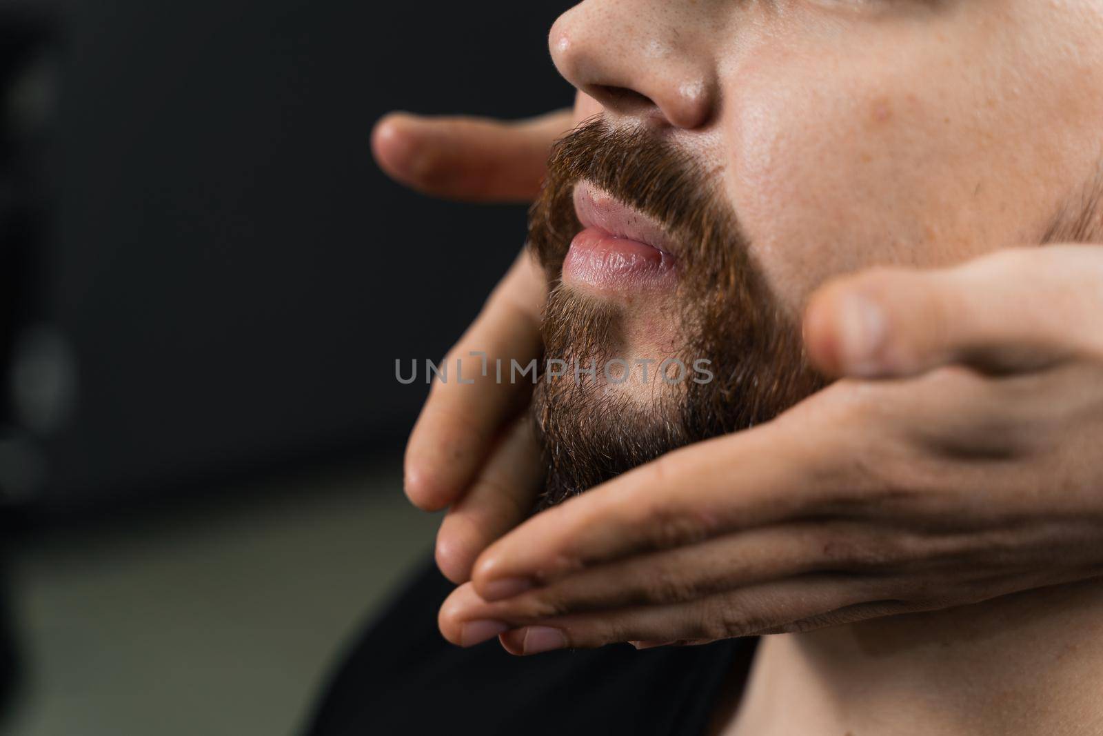 Fixing the shape of the beard with wax. The result of a haircut in a barbershop