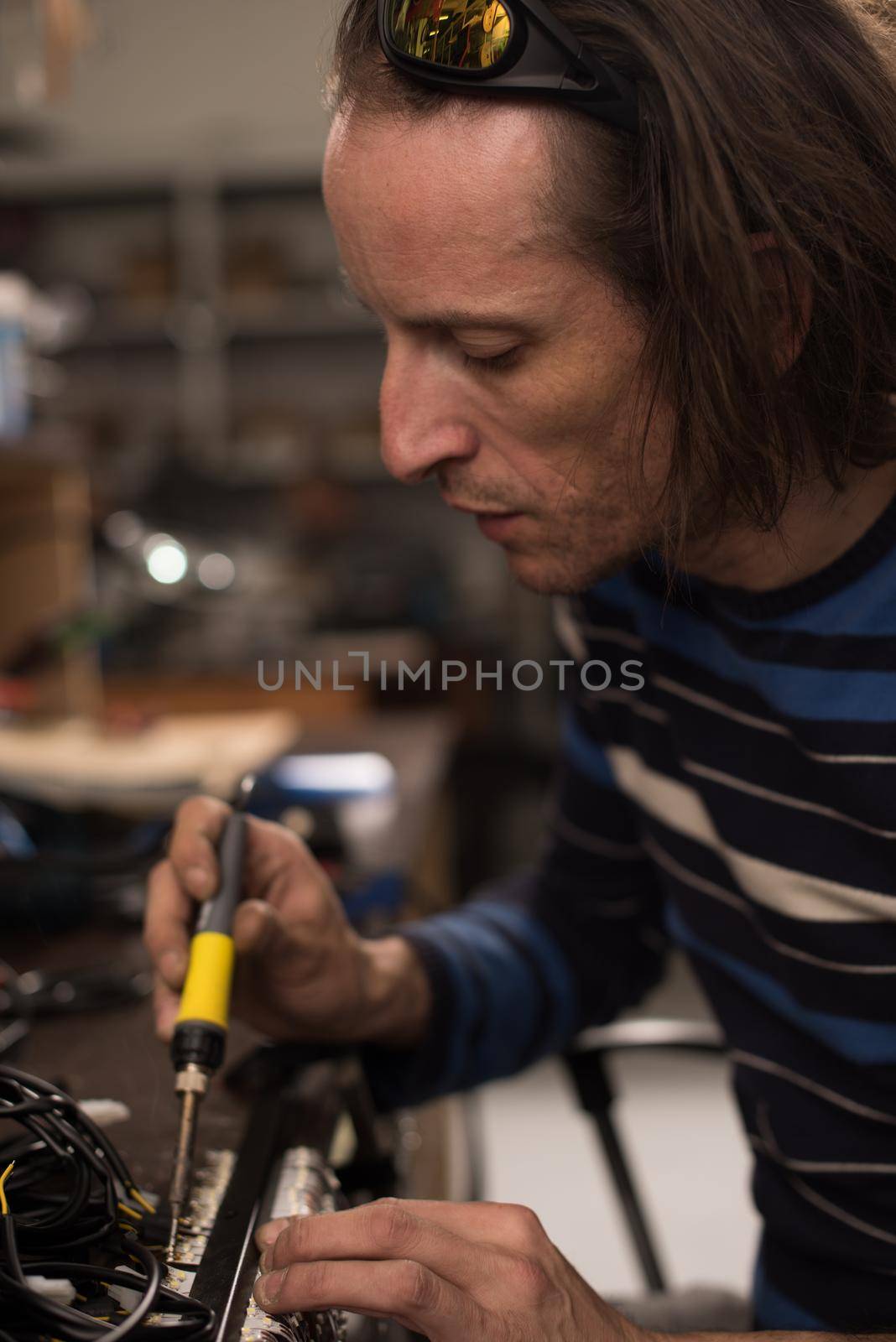 Industrial worker man soldering cables of manufacturing equipment in a factory. Selective focus. High quality photo