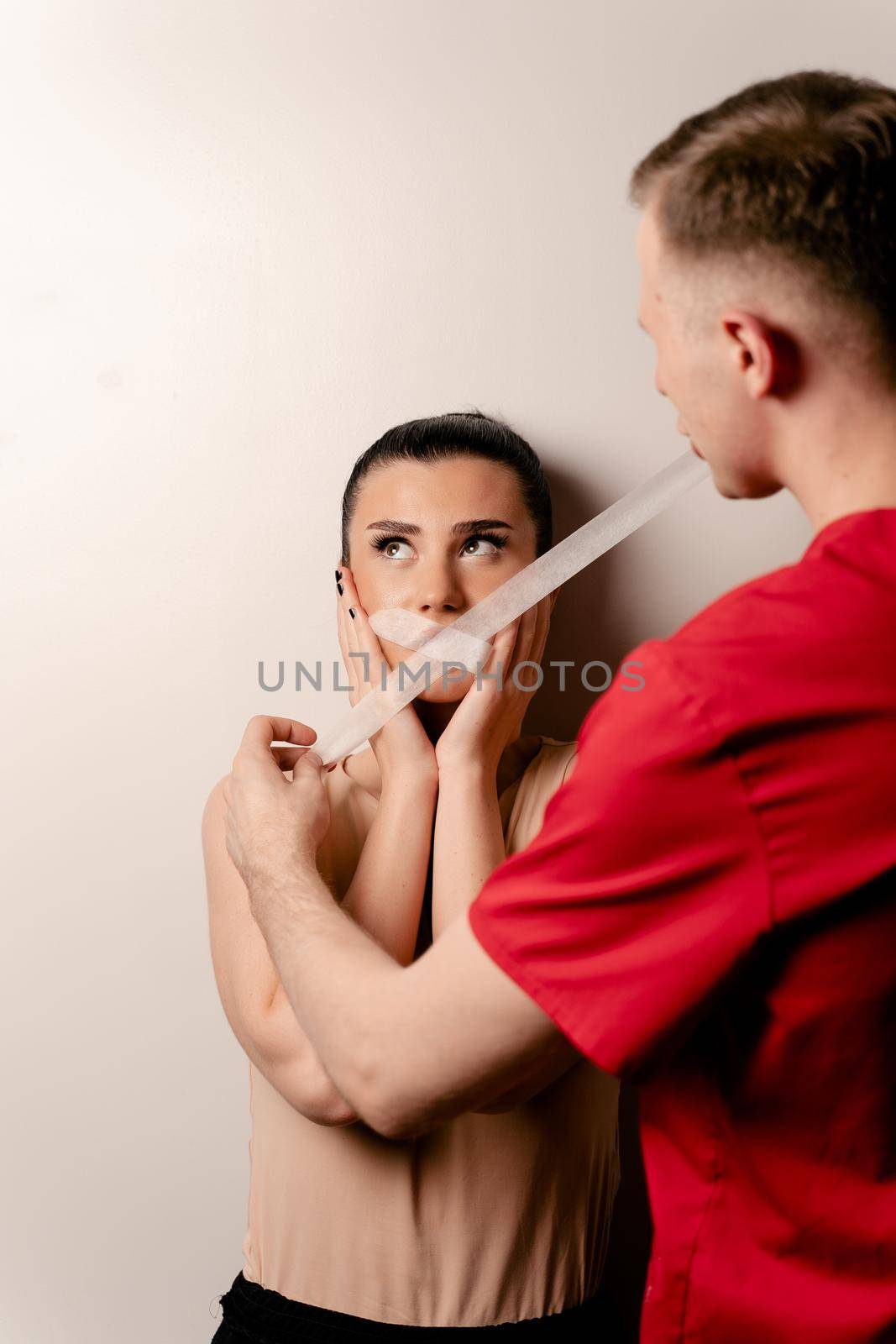 Model with glued mouth. Man covers woman mouth with tape. Stop talking