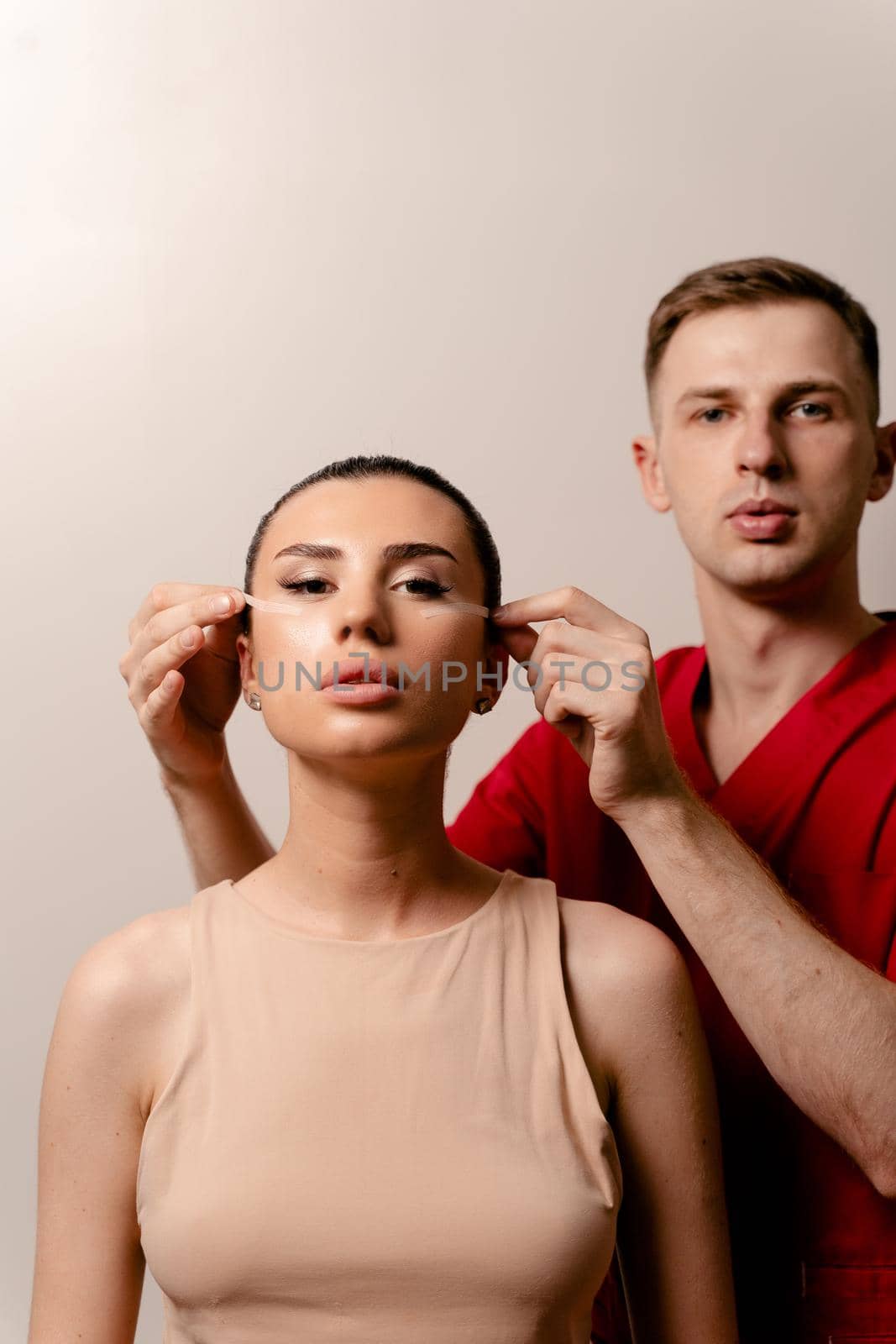 Facebuilding. Doctor with attractive female model. Blepharoplasty surgery