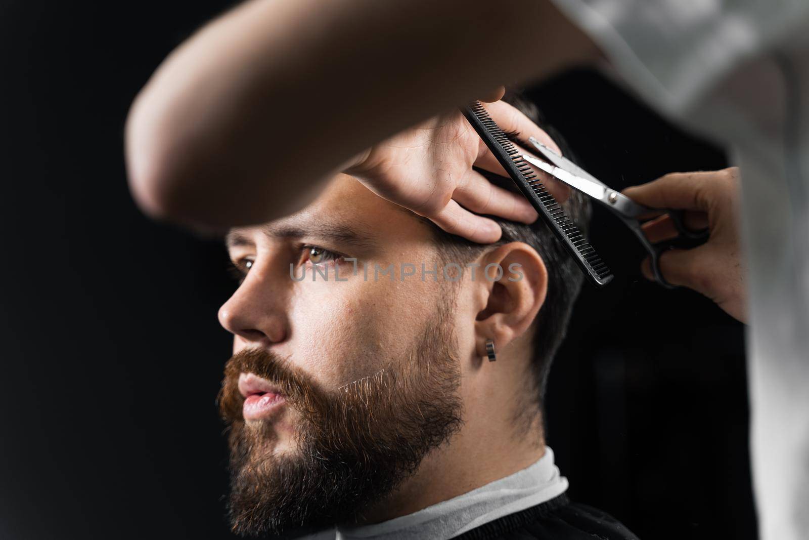 Barber making hairstyle for confident bearded hipster. Advertising for barbershop and men's beauty salon. by Rabizo