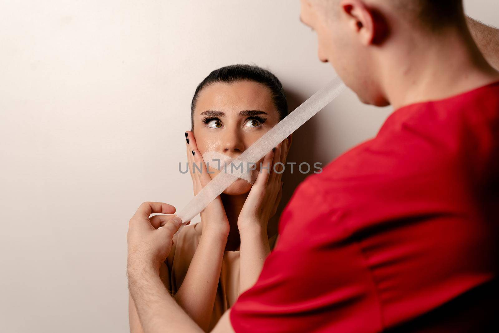 Model with glued mouth. Man covers woman mouth with tape. Stop talking