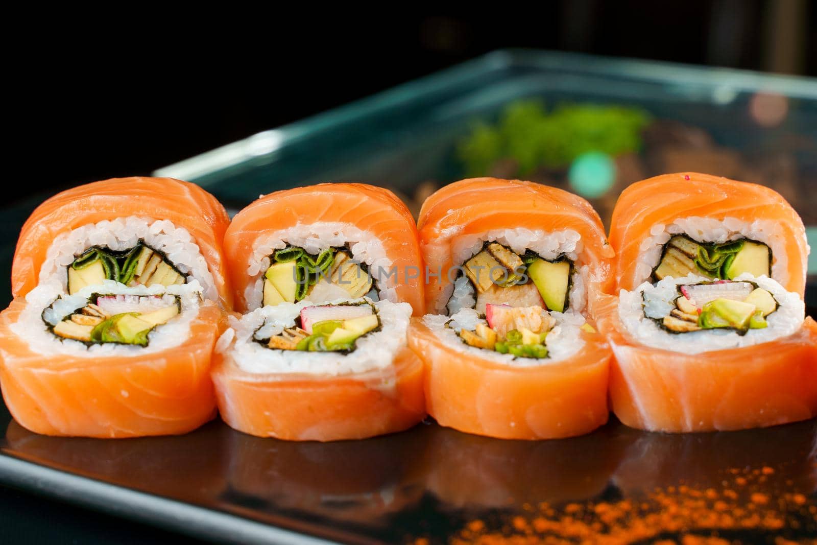 Roll with salmon, eel, avocado, crab, green onion close-up. Traditional Japanese cuisine.