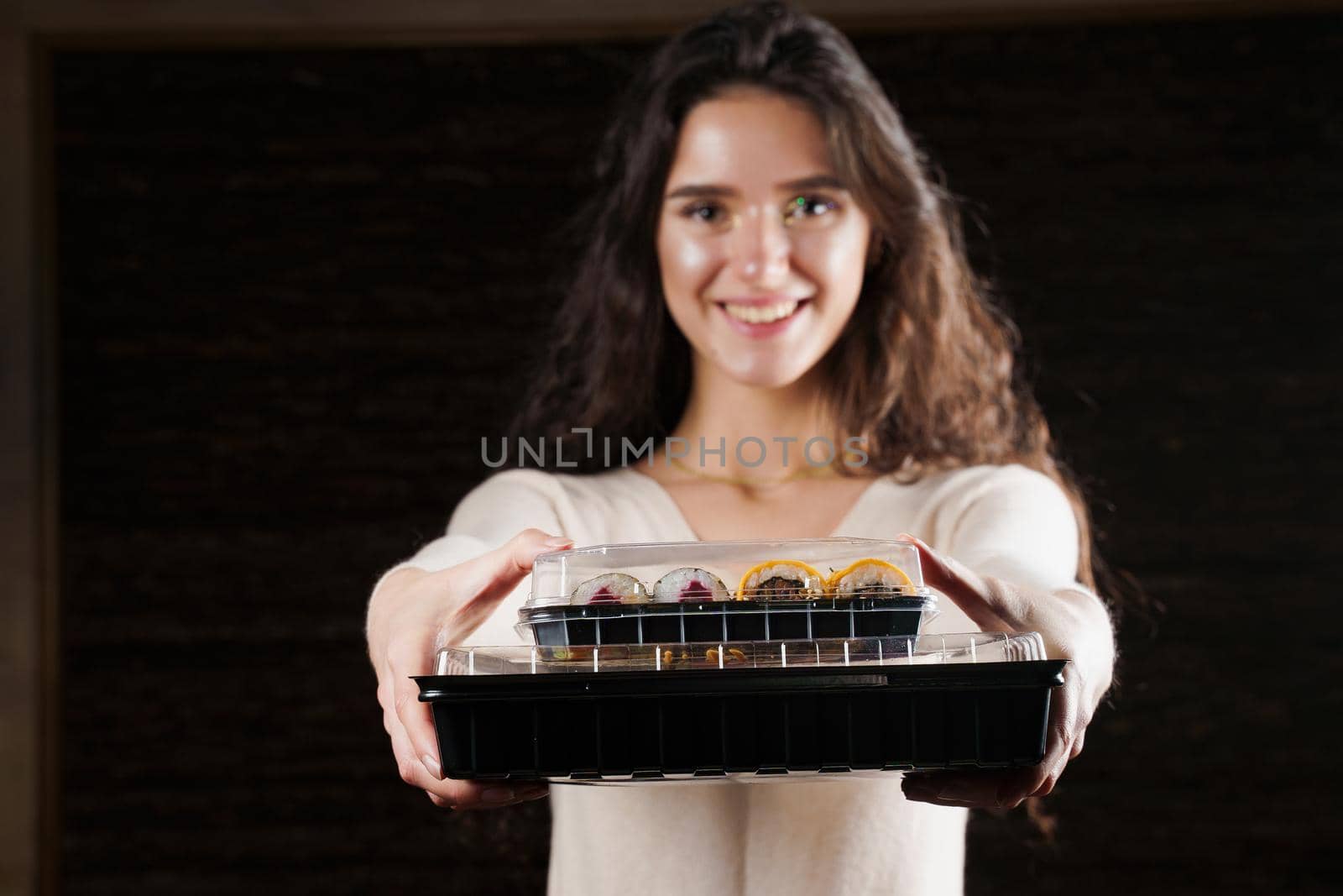 Sushi set in box healthy food delivery service. Girl courier with 2 sushi boxes. Japanese cuisine: rolls, soy sauce, wasabi.