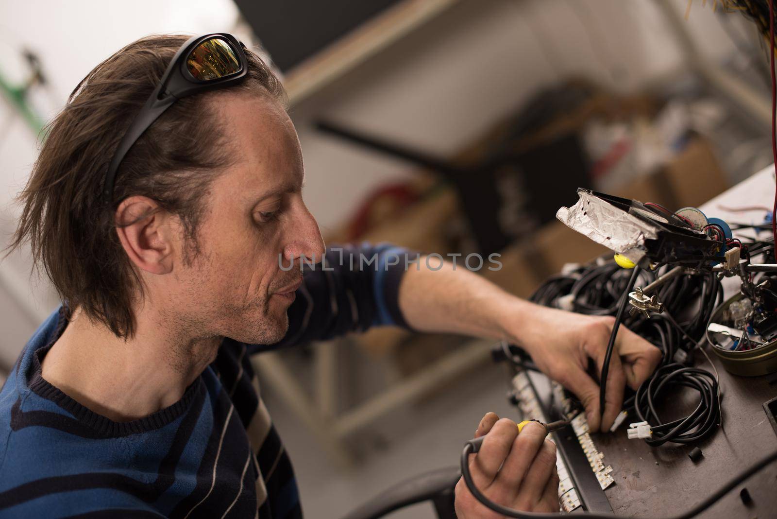 Industrial worker man soldering cables of manufacturing equipment in a factory. Selective focus. High quality photo