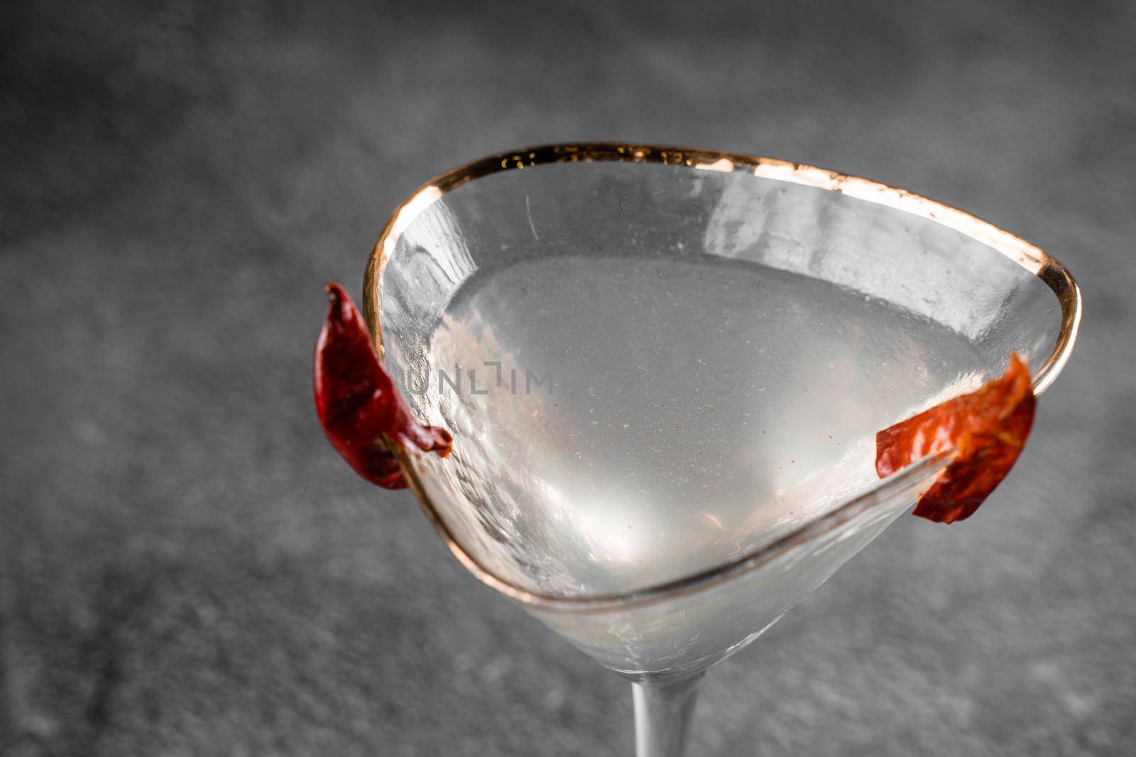 Cocktail in glass with chili on gray background. Devil alcohol drink