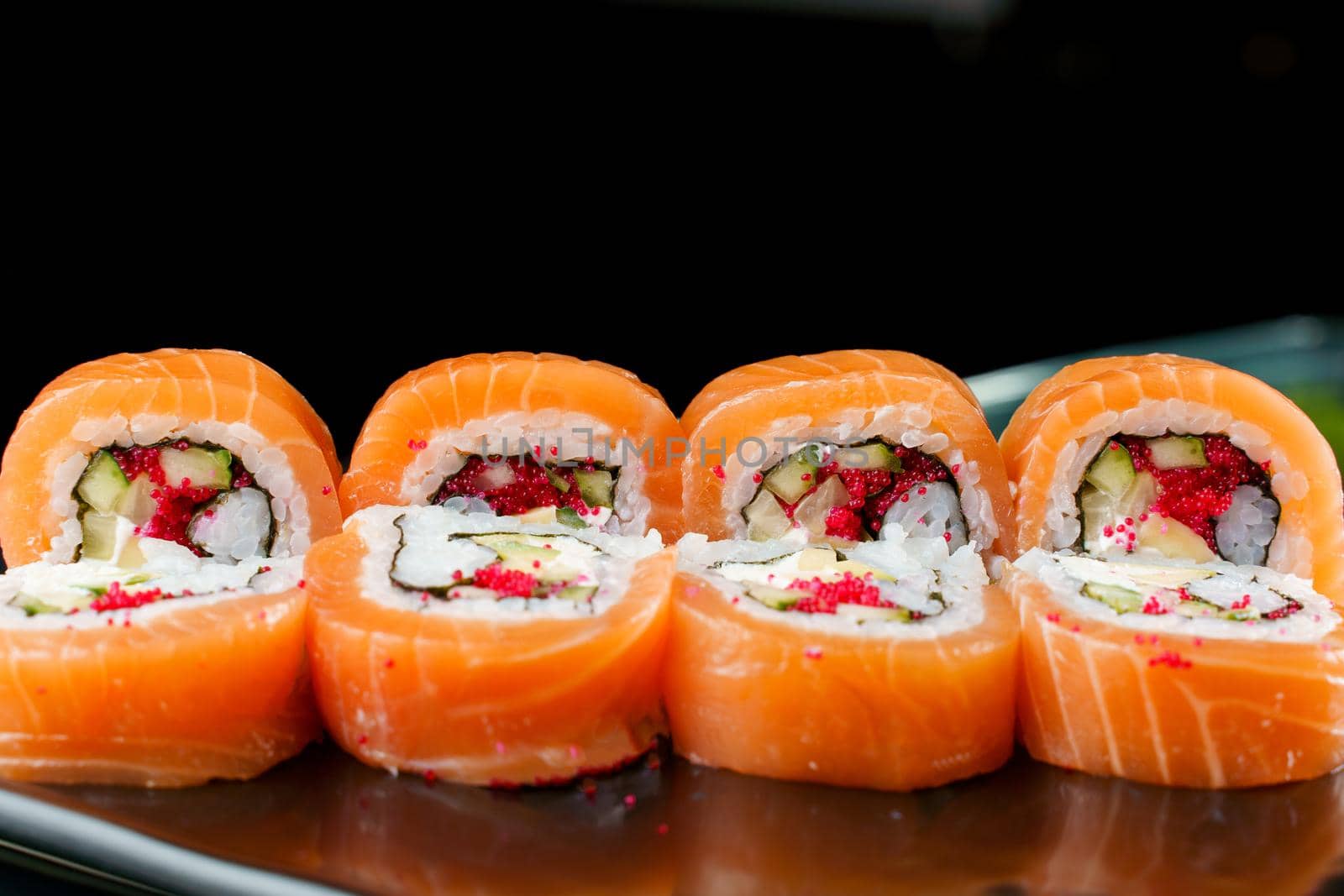 Rolls with salmon, tobiko caviar, avocado, cucumber, nori close-up. Traditional Japanese cuisine. by Rabizo