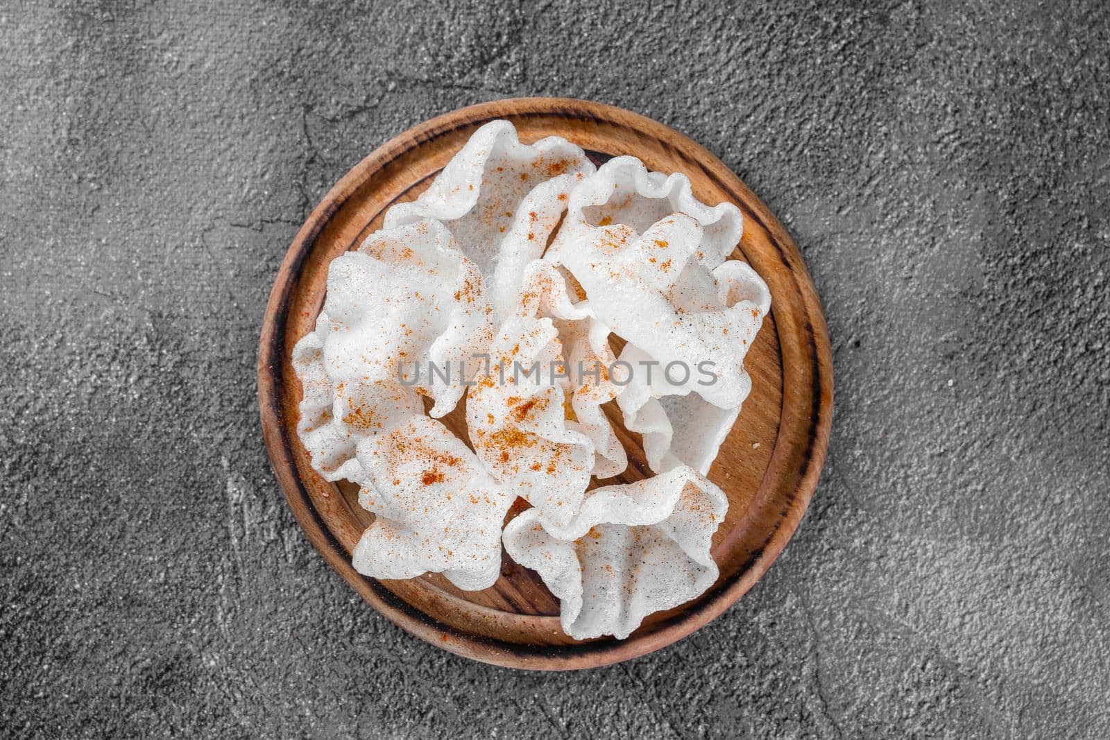 Rice chips on a wooden board on a gray background. Top view