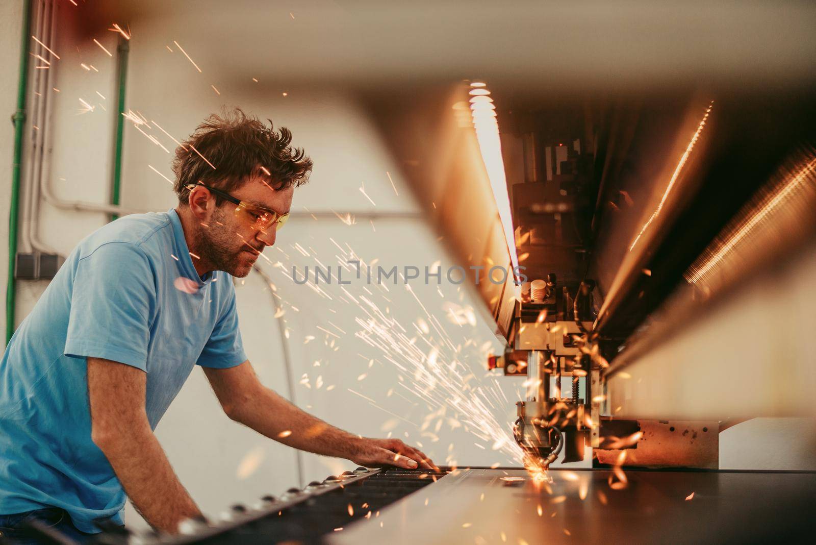 Within heavy industry. A man works in a modern factory on a CNC machine. Selective focus. High-quality photo