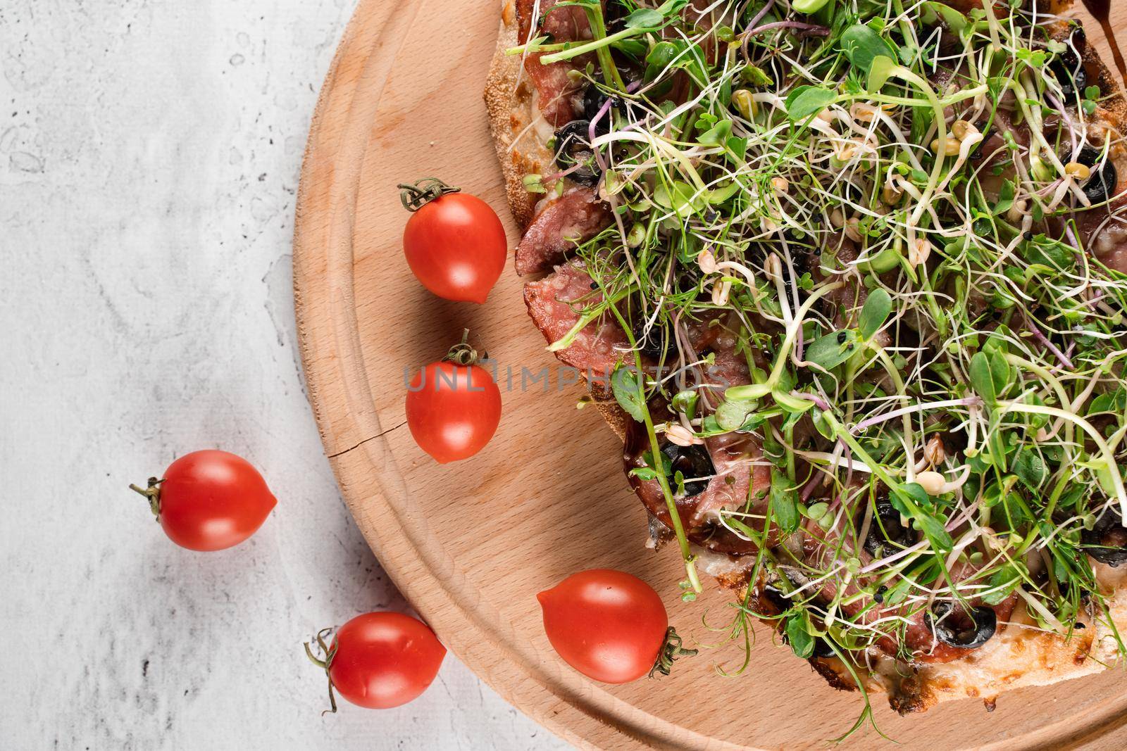 Pinsa romana with salami, cheese, mushrooms, decorated with microgreens on wooden boardon white background. by Rabizo