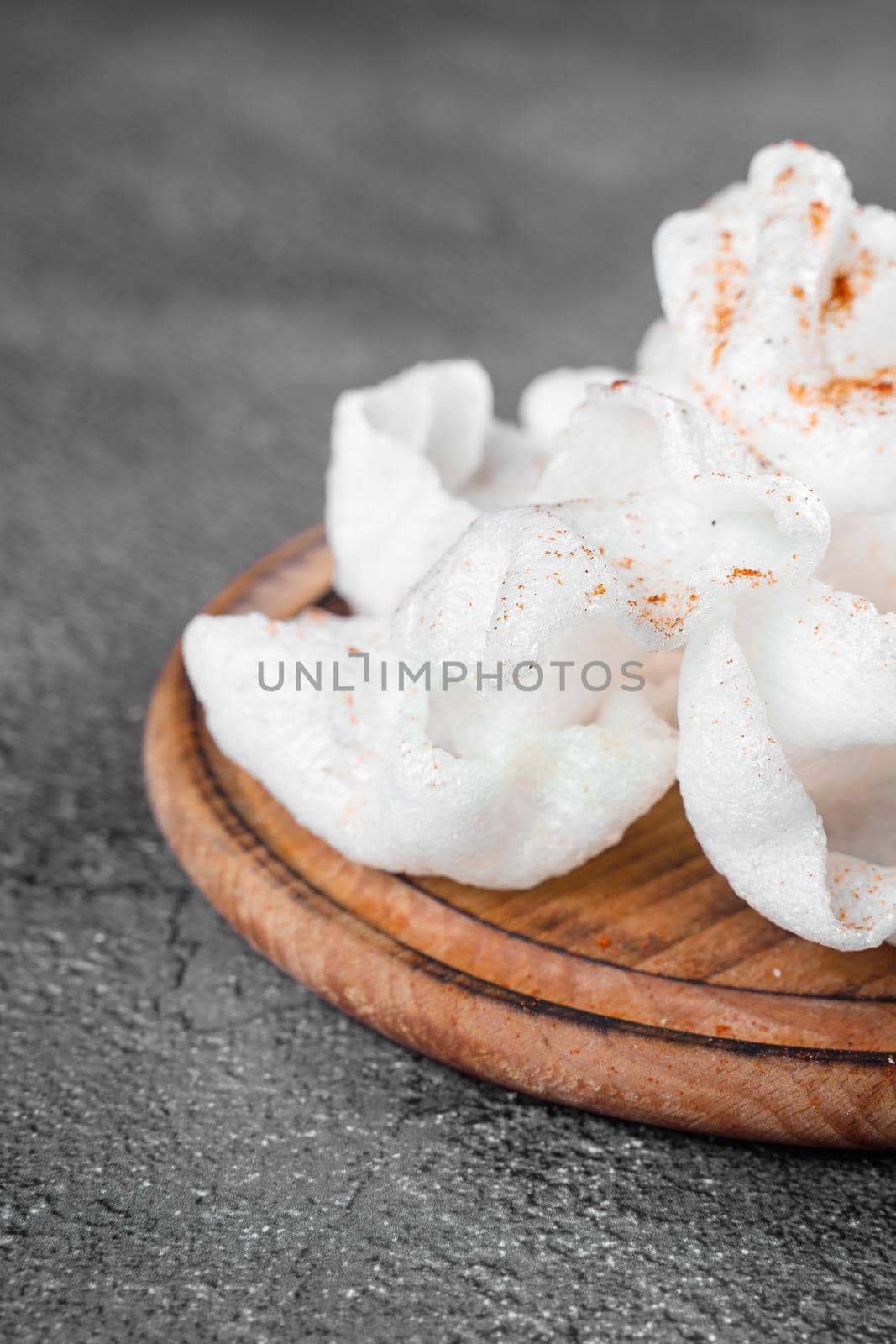 Rice paper chips fried in oil. Rice chips on a wooden board on gray background. by Rabizo