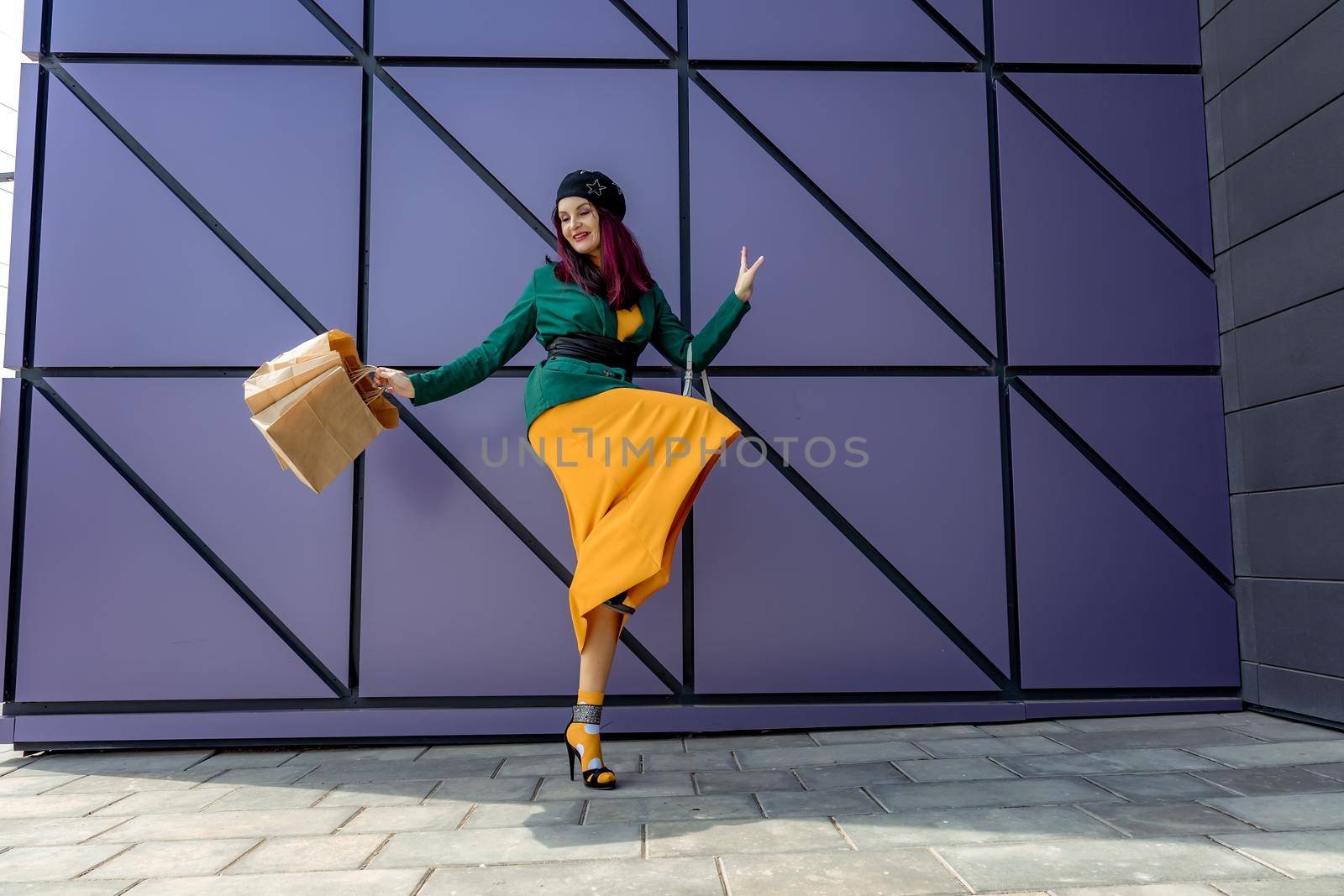 A happy shopaholic girl throws her bags near a shopping center. Have fun shopping on Black Friday. the girl in the store is happy with her purchases, throws packages. Consumer concept