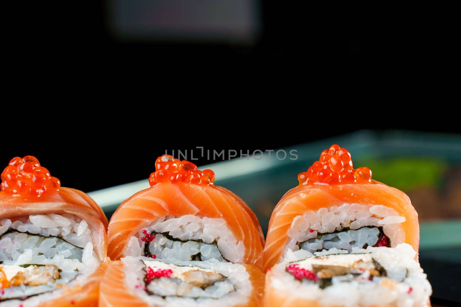 Roll red dragon with salmon, red caviar, tobiko, eel, rice, nori close-up. Sushi traditional Japanese cuisine