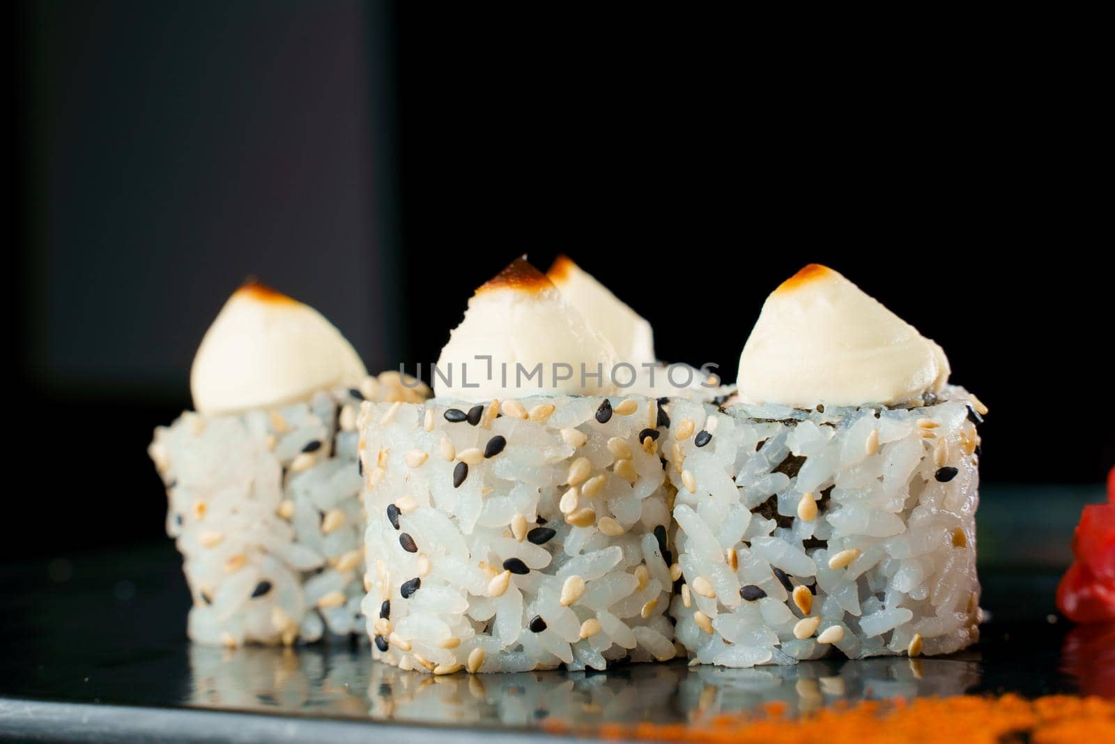 Baked rolls in black and white sesame with cream cheese close-up. Sushi Japanese cuisine by Rabizo