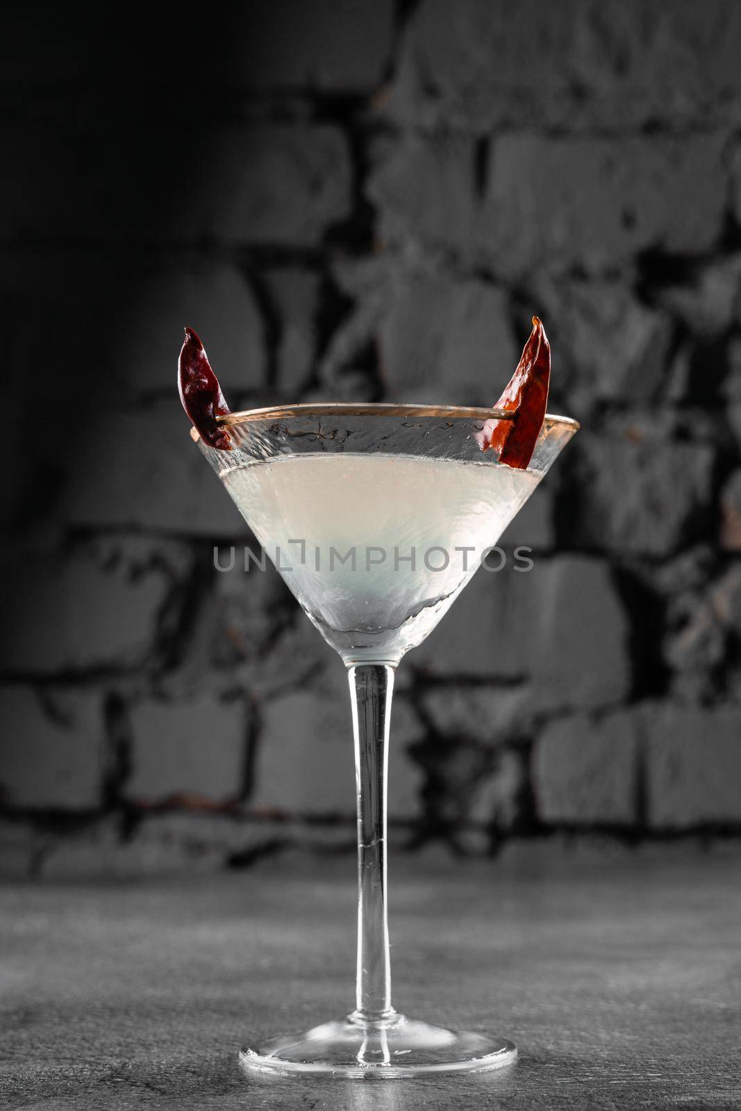 Cocktail in glass with chili on gray background. Devil alcohol drink