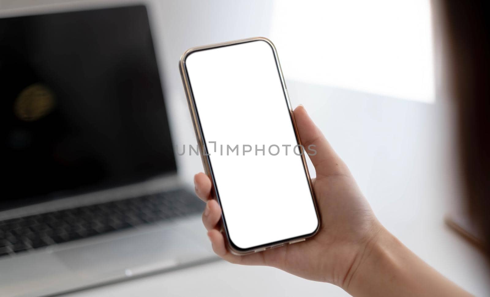 Cropped shot view of woman hands holding smart phone with blank copy space screen for your text message or information content, female reading text message on cell telephone during in office. by wichayada